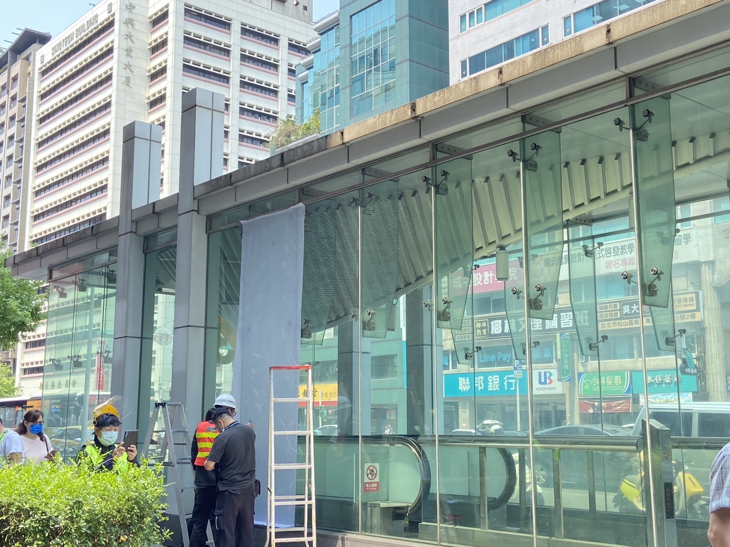 捷運南京三民站3號出口玻璃因地震呈碎裂痕，人員緊急處置。（讀者提供）