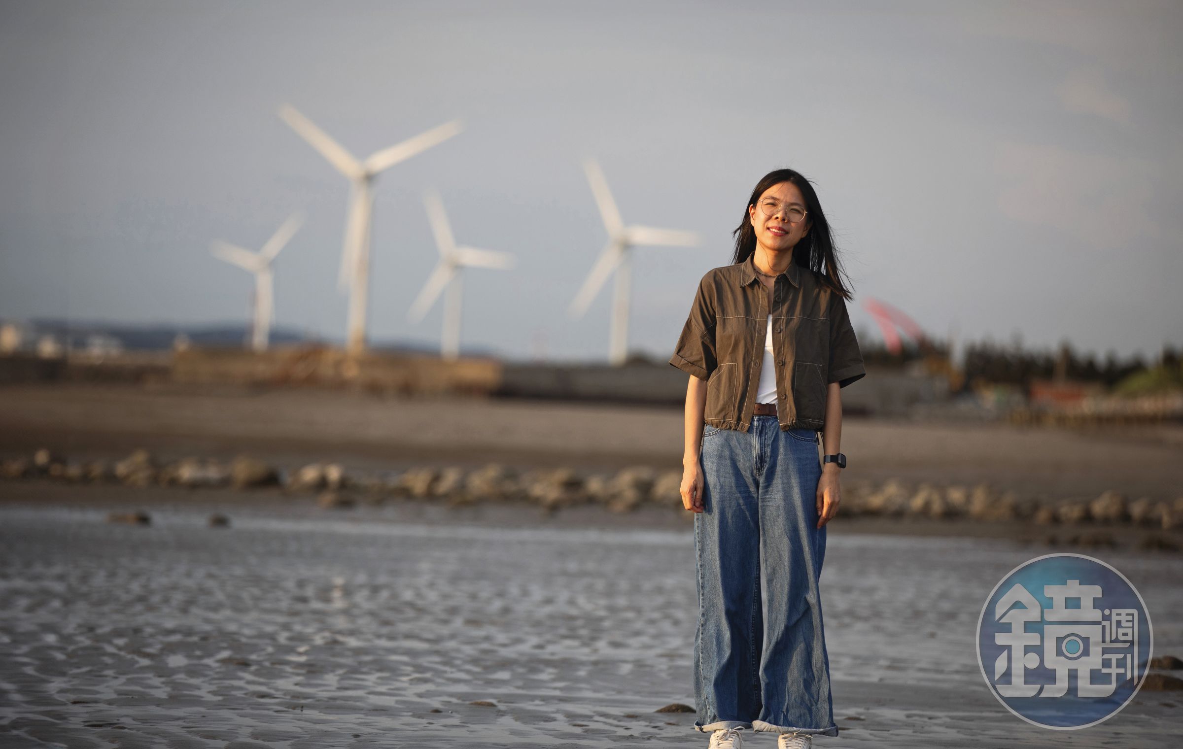 劉育育在苑裡海邊，遠處有風力發電機組，是濱海鄉鎮常見風景。