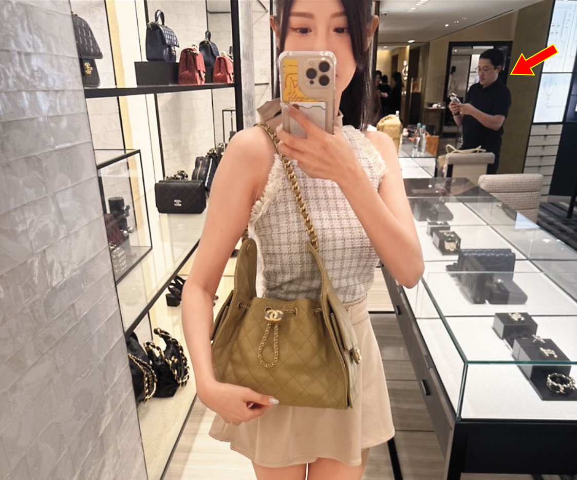 許玲玲在晶華酒店挑選精品包自拍，在後面的梁為超（箭頭處）也入鏡。（讀者提供）