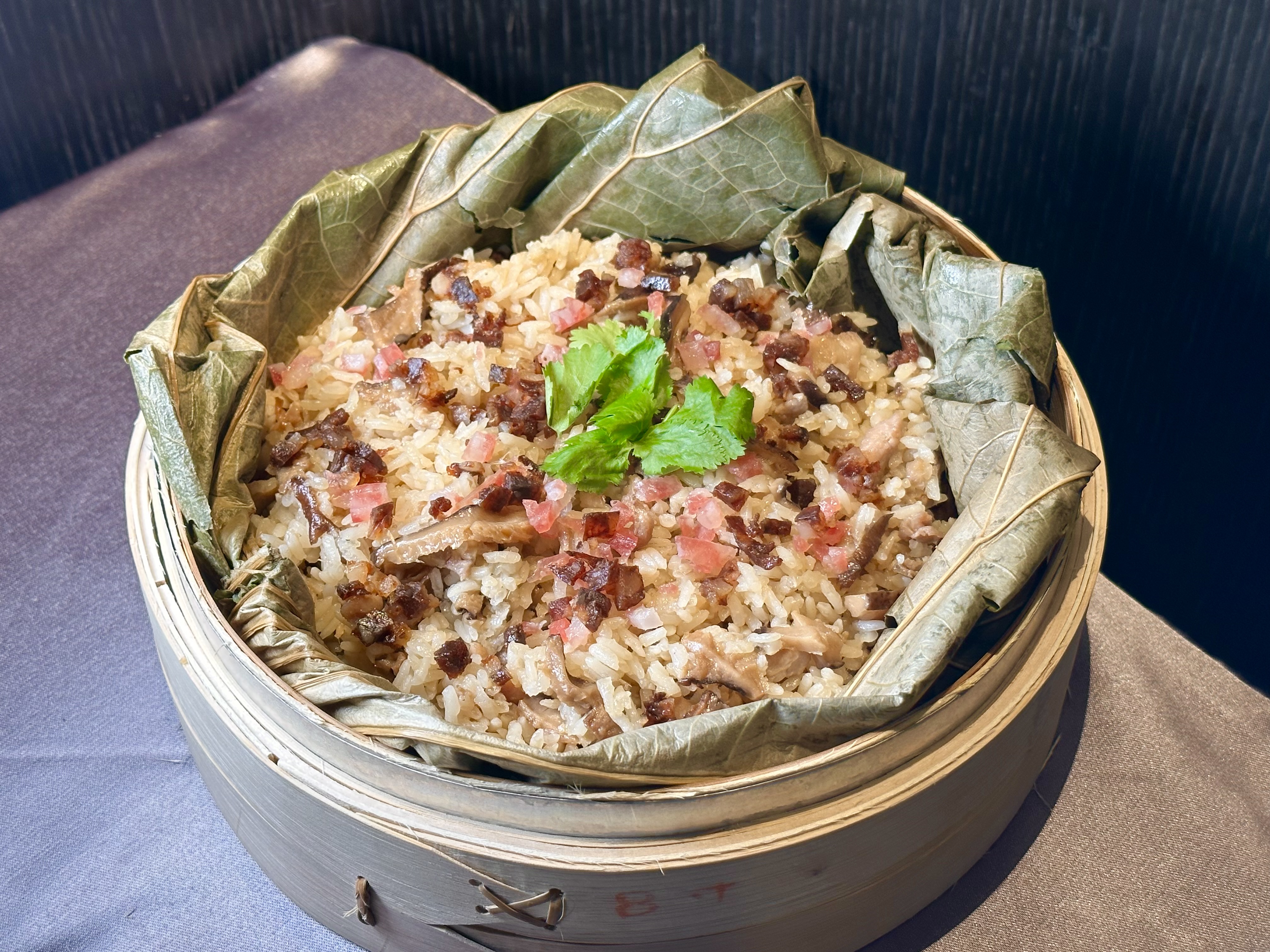 「西港麻油臘腸土雞飯」荷葉香撲鼻，米粒濕軟有麻油味，還摻著鹹香臘腸丁。（580元／份）