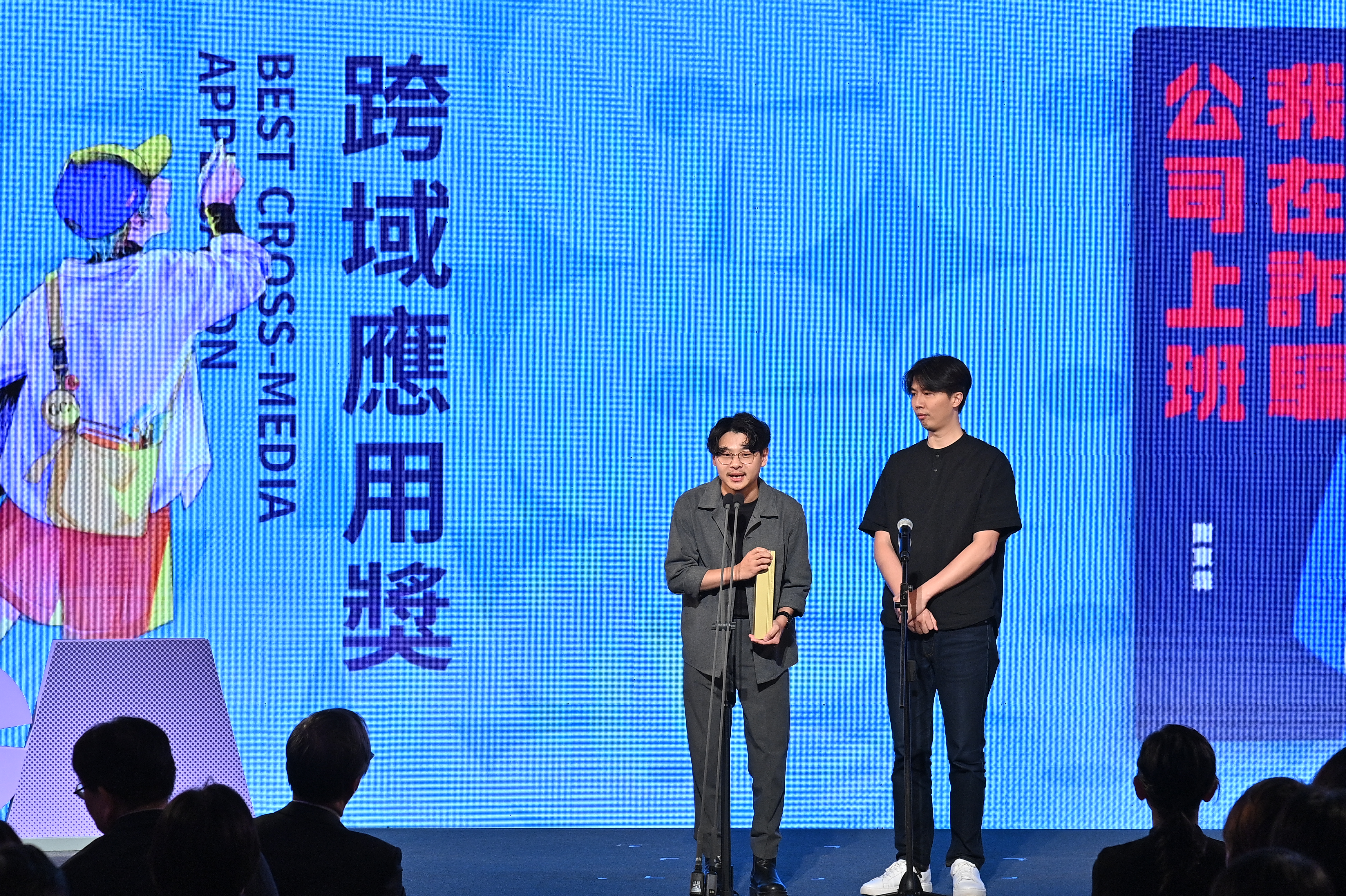 跨域應用獎由果陀劇場製作的《我在詐騙公司上班》音樂劇獲得,導演蘇昱瑋(左)與漫畫家謝東霖(右)上台領獎。