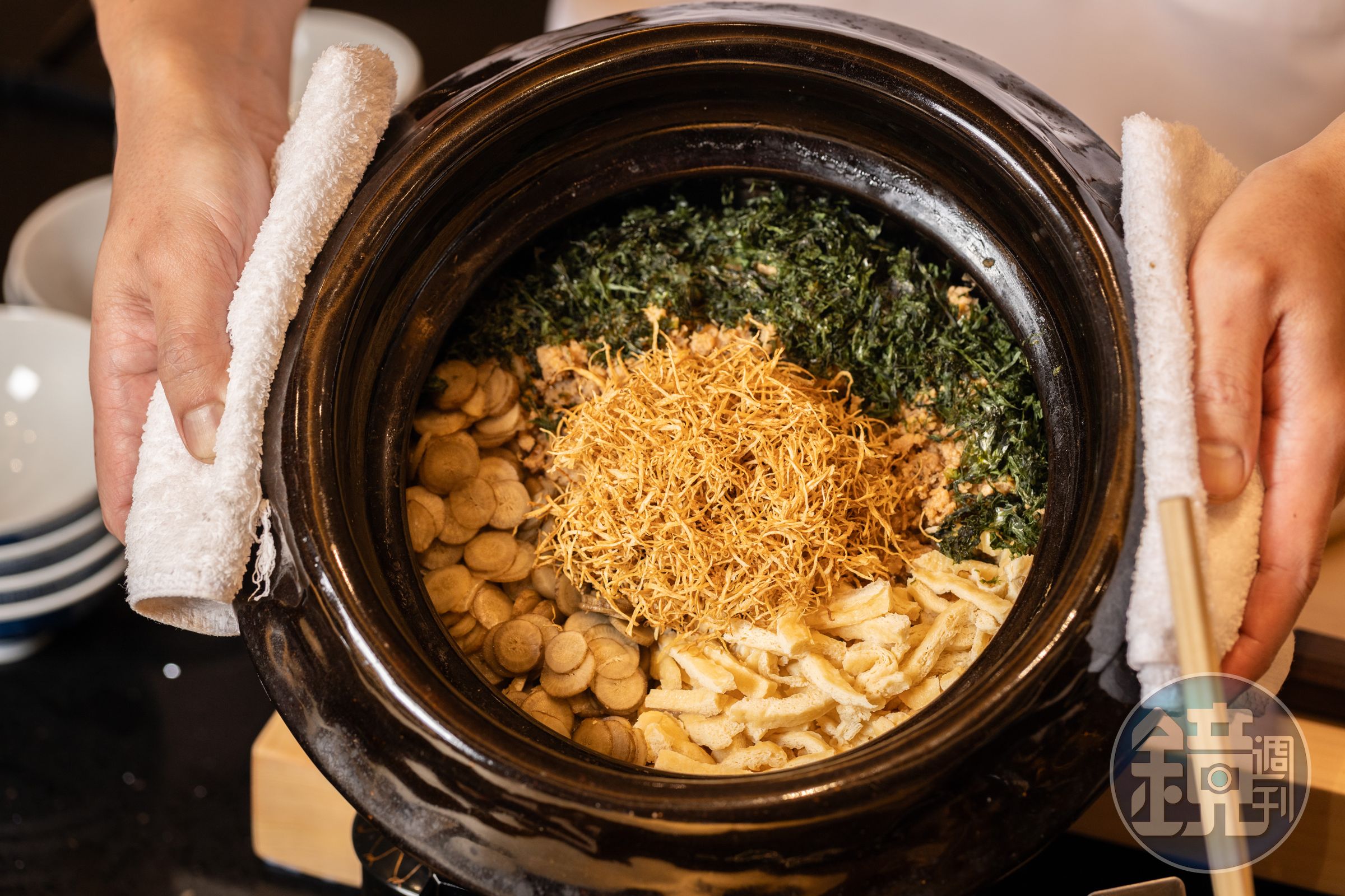 「牛蒡雞鬆釜飯」使用日本山形豔姬米與雲井窯土鍋煮製，搭配油揚、海苔、炸牛蒡絲、牛蒡片與雞肉鬆，打造頂級鄉土美味。（3,800元套餐菜色）