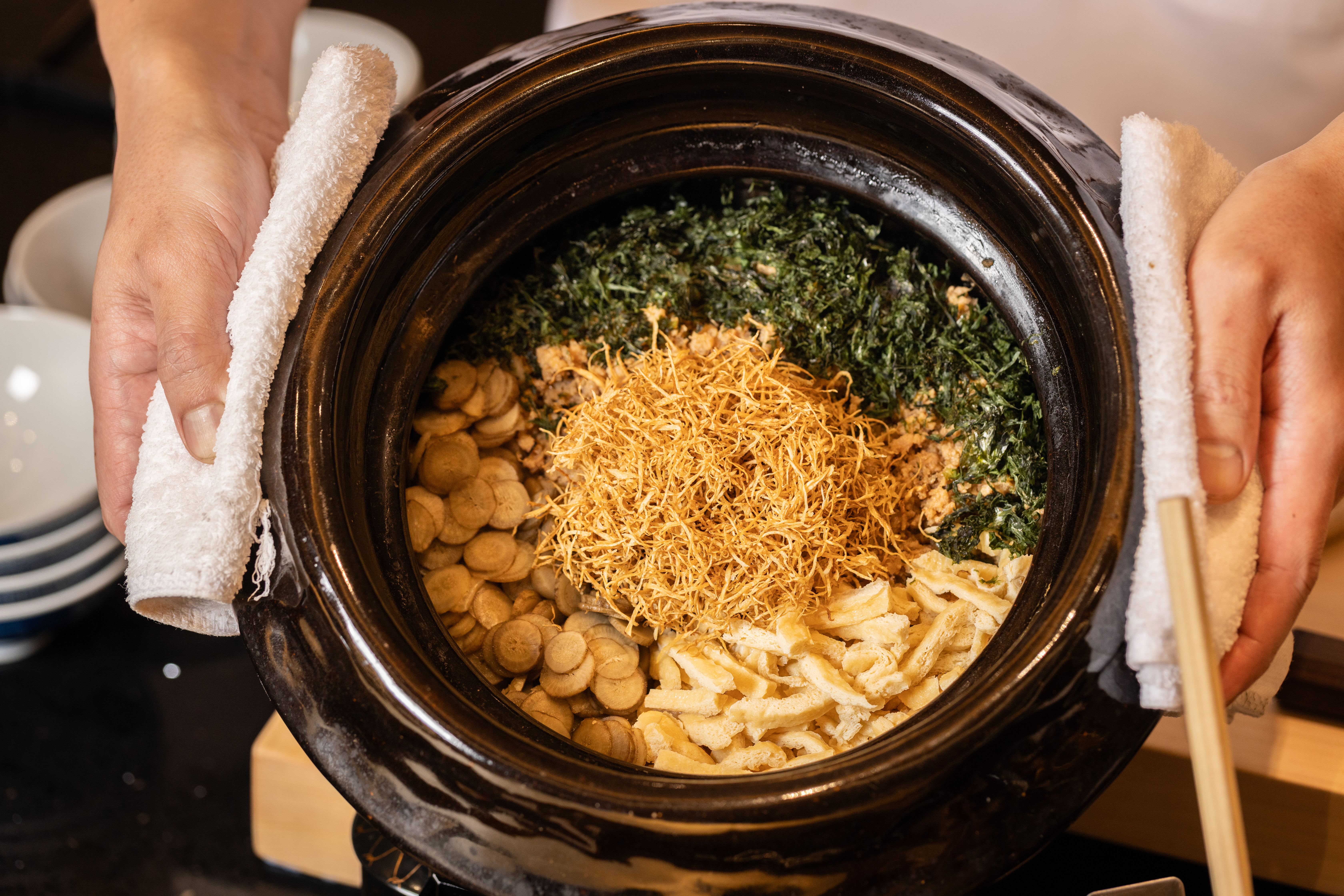 「牛蒡雞鬆釜飯」使用日本山形豔姬米與雲井窯土鍋煮製,搭配油揚、海苔、炸牛蒡絲、牛蒡片與雞肉鬆,打造頂級鄉土美味。(3,800元套餐菜色)