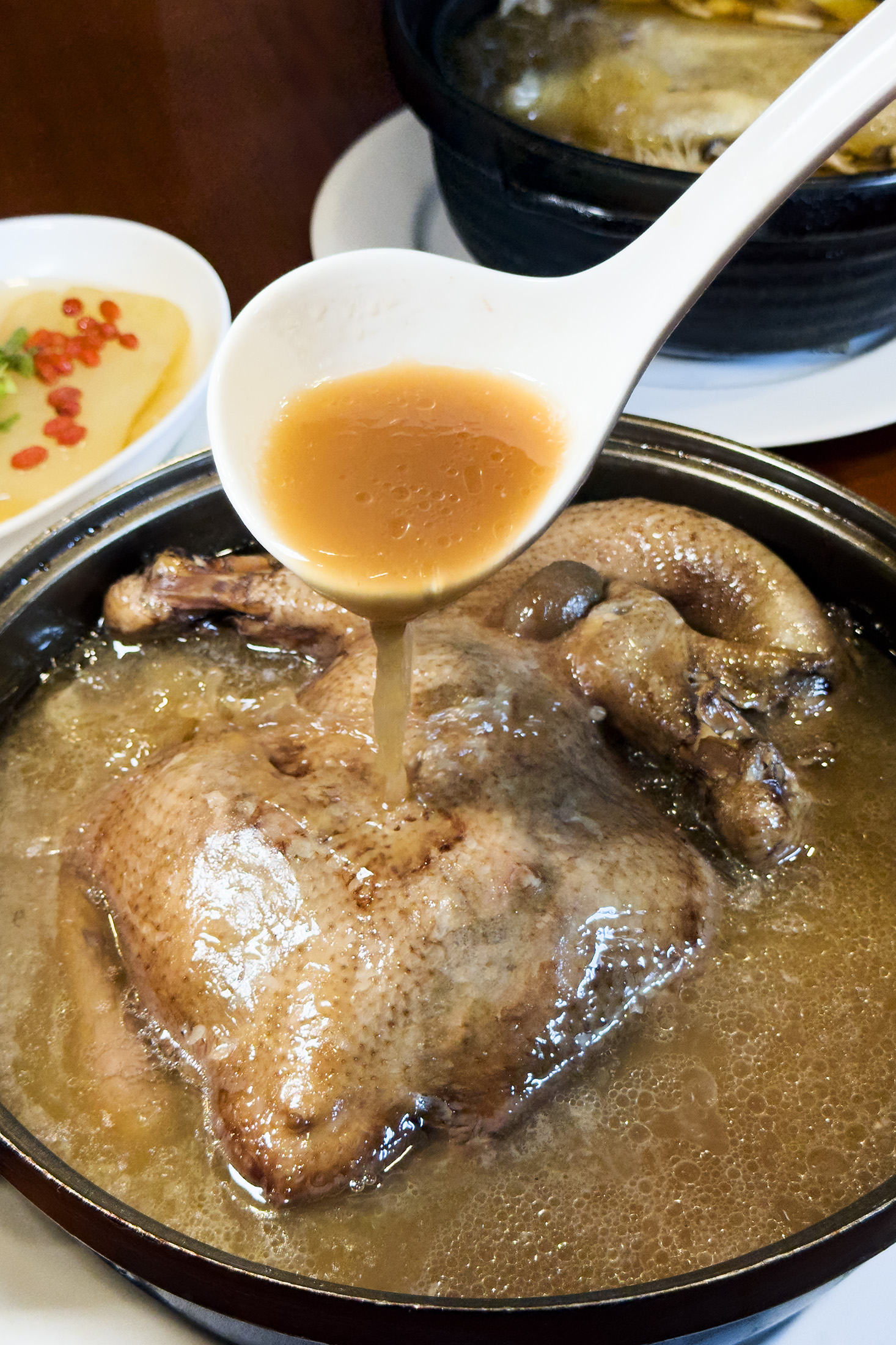 「黑金菜脯全雞」以三種不同年份老菜脯煨煮出的湯頭深邃厚實，展現慢火燉煮的火候功力。