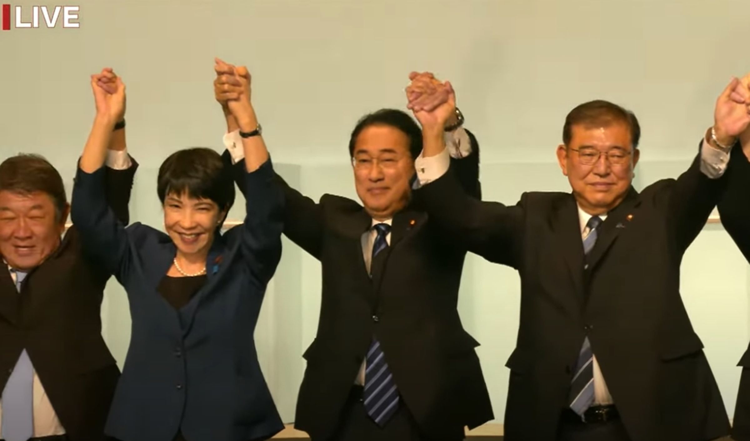 選舉結果公布後,現任首相岸田文雄(中)牽起高市、石破的手,所有候選人手牽手營造大團結氣勢。(翻攝自民黨YouTube直播)