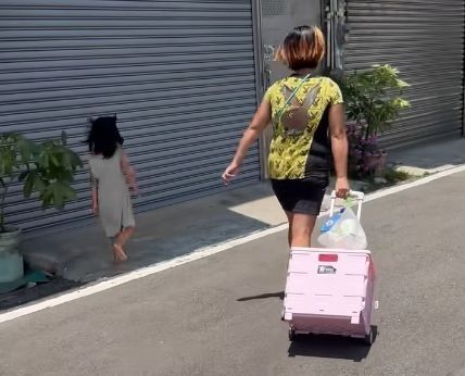 小孩子受不了疼痛，試圖躲到陰影處，卻被媽媽一把拉回太陽底下繼續踩在滾燙的柏油路上走。（翻攝自臉書社團「新竹大小事」）