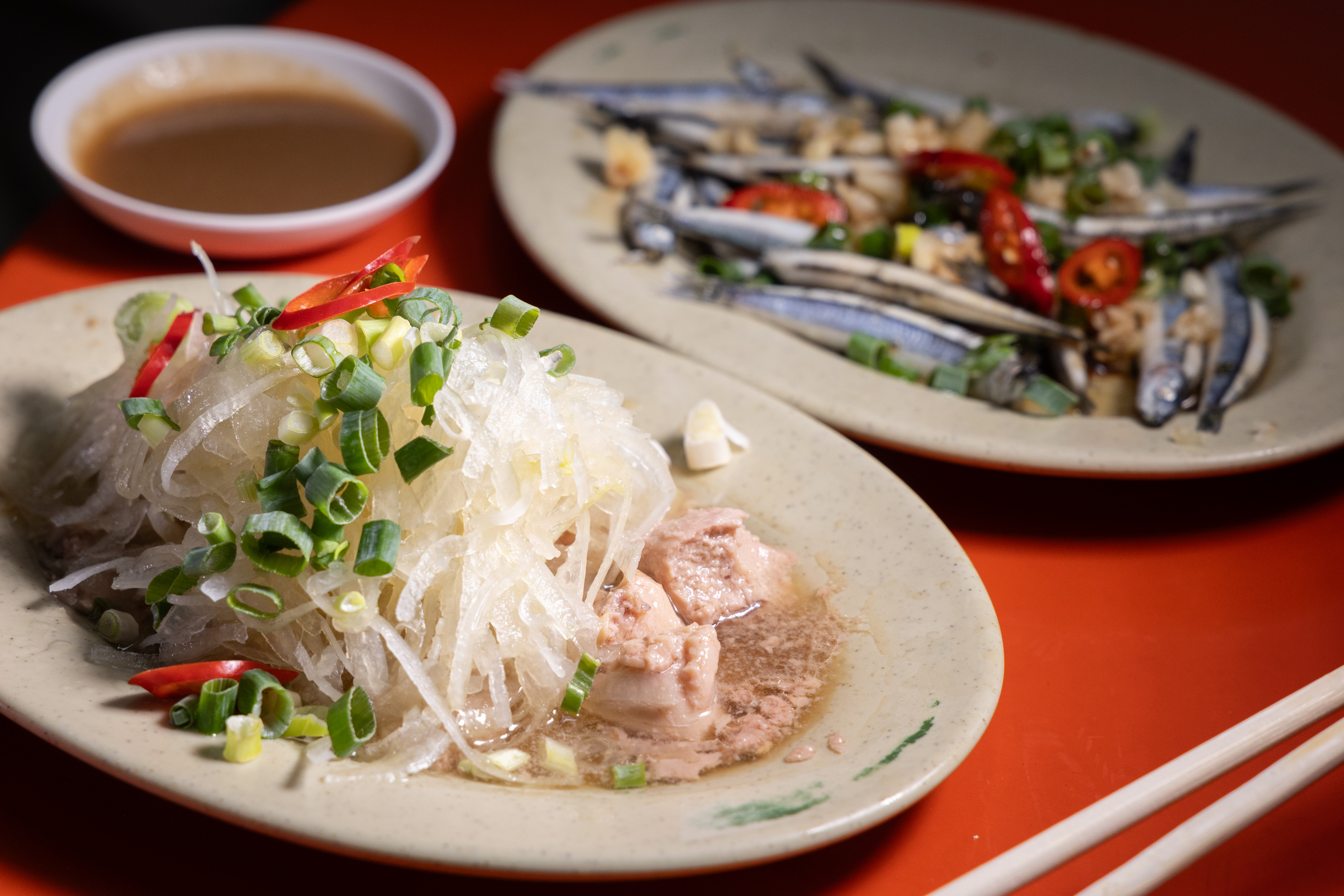 「洋蔥鱈魚肝」(前)的洋蔥絲酸甜解膩,肥美飽滿的「丁香魚」只以涼拌處理就很好吃。(皆200元/份)