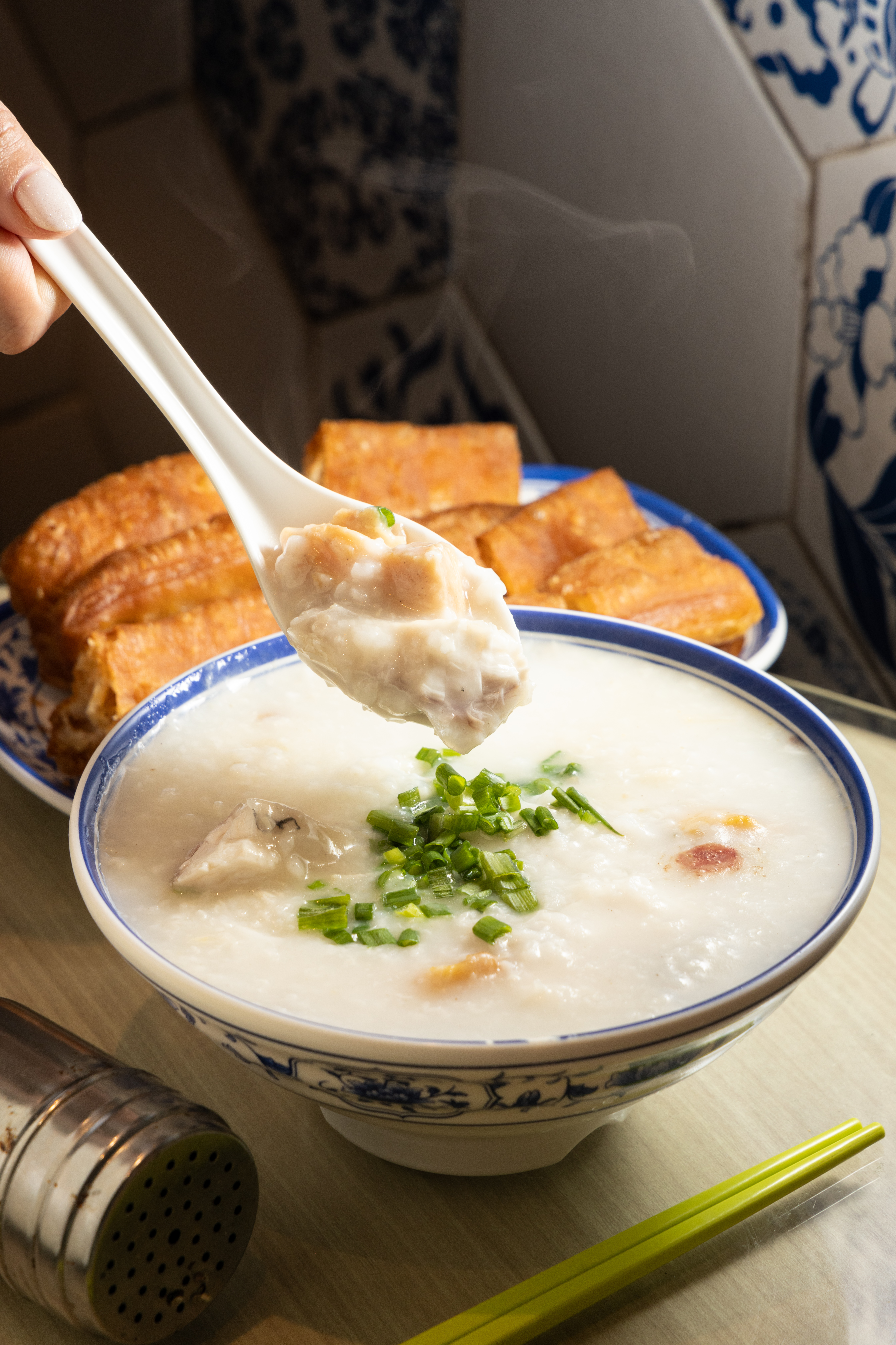 料多實在的「魚腩滑雞粥」鮮味十足（前，港幣50元／碗）佐上「香脆油條」（後，港幣11元／份）才對味。