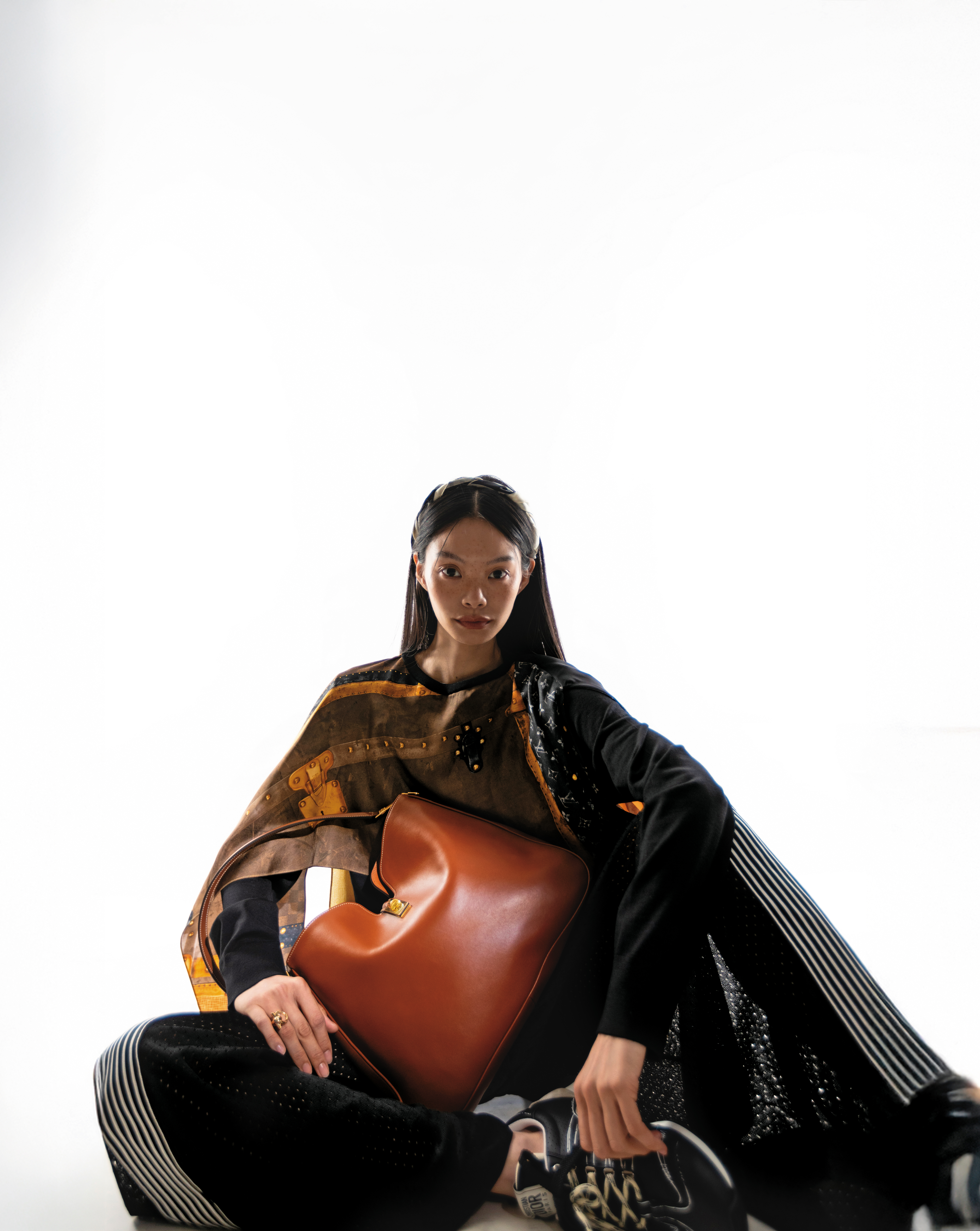 CAMILLE 16 SOFT棕褐色光滑牛皮革中型手袋 NT$110,000 by CELINE by HEDI SLIMANE；披肩造型上衣 價格未定 by LOUIS VUITTON；黑色寬褲 NT$100,000 by DIOR；D-Sketch黑色科技布料拼接小牛皮運動鞋 NT$35,000 by DIOR；髮帶（領巾） 價格未定 by LOUIS VUITTON Ganpierc金色戒指 NT$11,900 by FERRAGAMO。