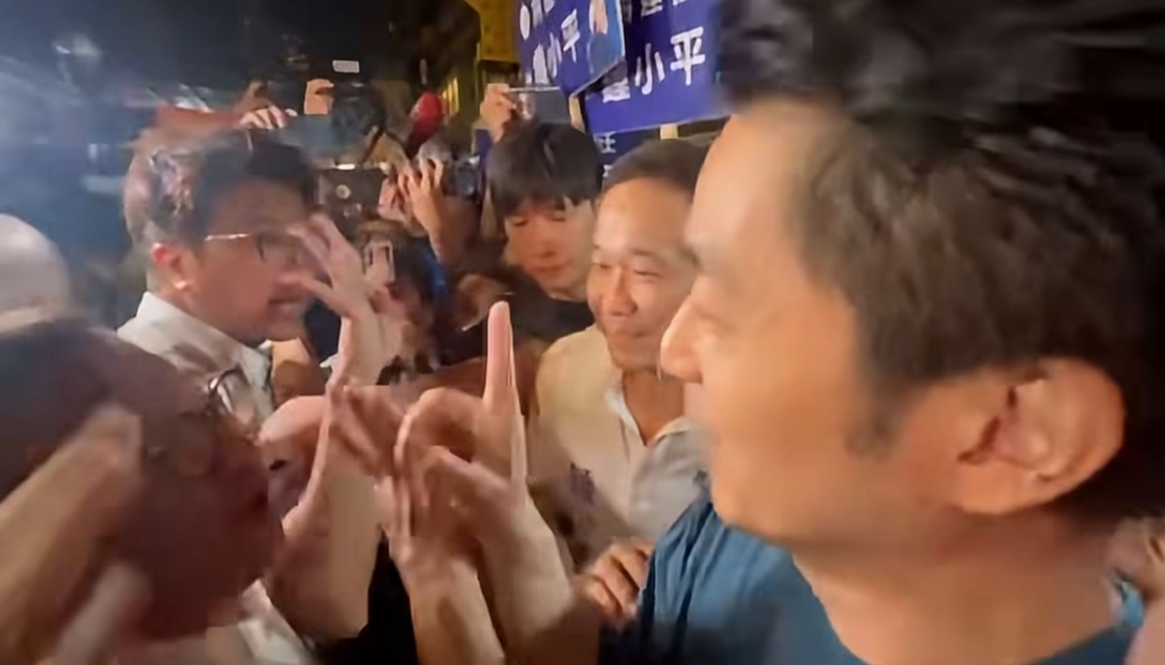 沈伯洋不斷比「4」，當眾邀請進行4場辯論，蔣萬安則不斷比「1」，強調先派員進行第一場辯論的協商。（翻攝自周軒臉書）