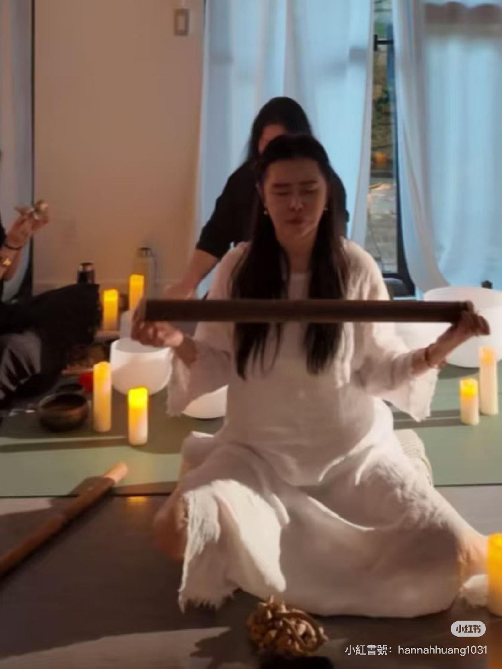 王祖賢盤腿坐著，手上拿雨棍。（翻攝小紅書）