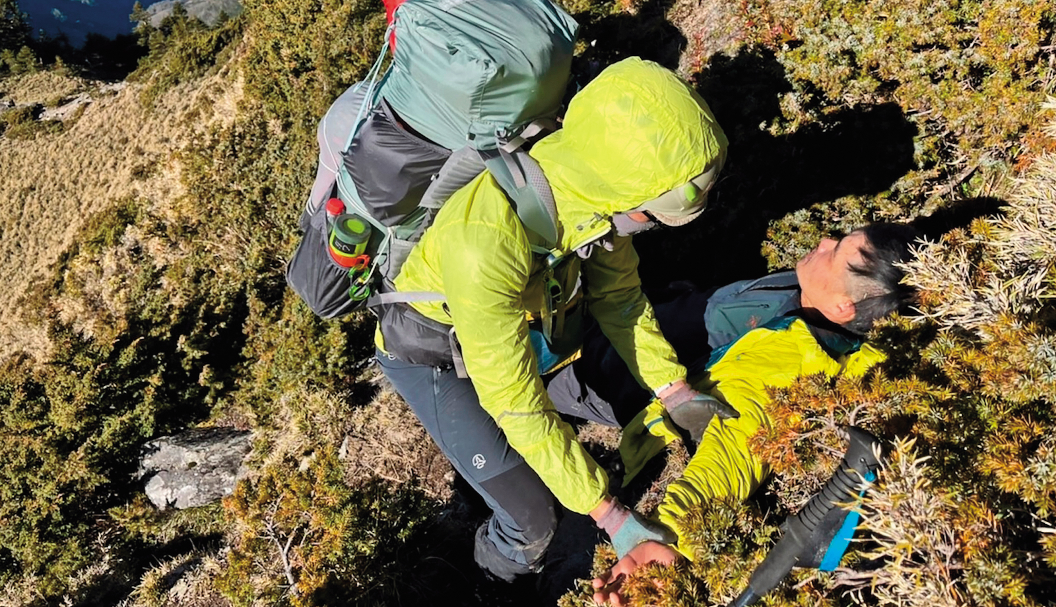 楊守義（右）於南橫公路以南至卑南主山間訓練途中不慎摔落山坡，現場夥伴緊急協助下山。（活水文化提供）