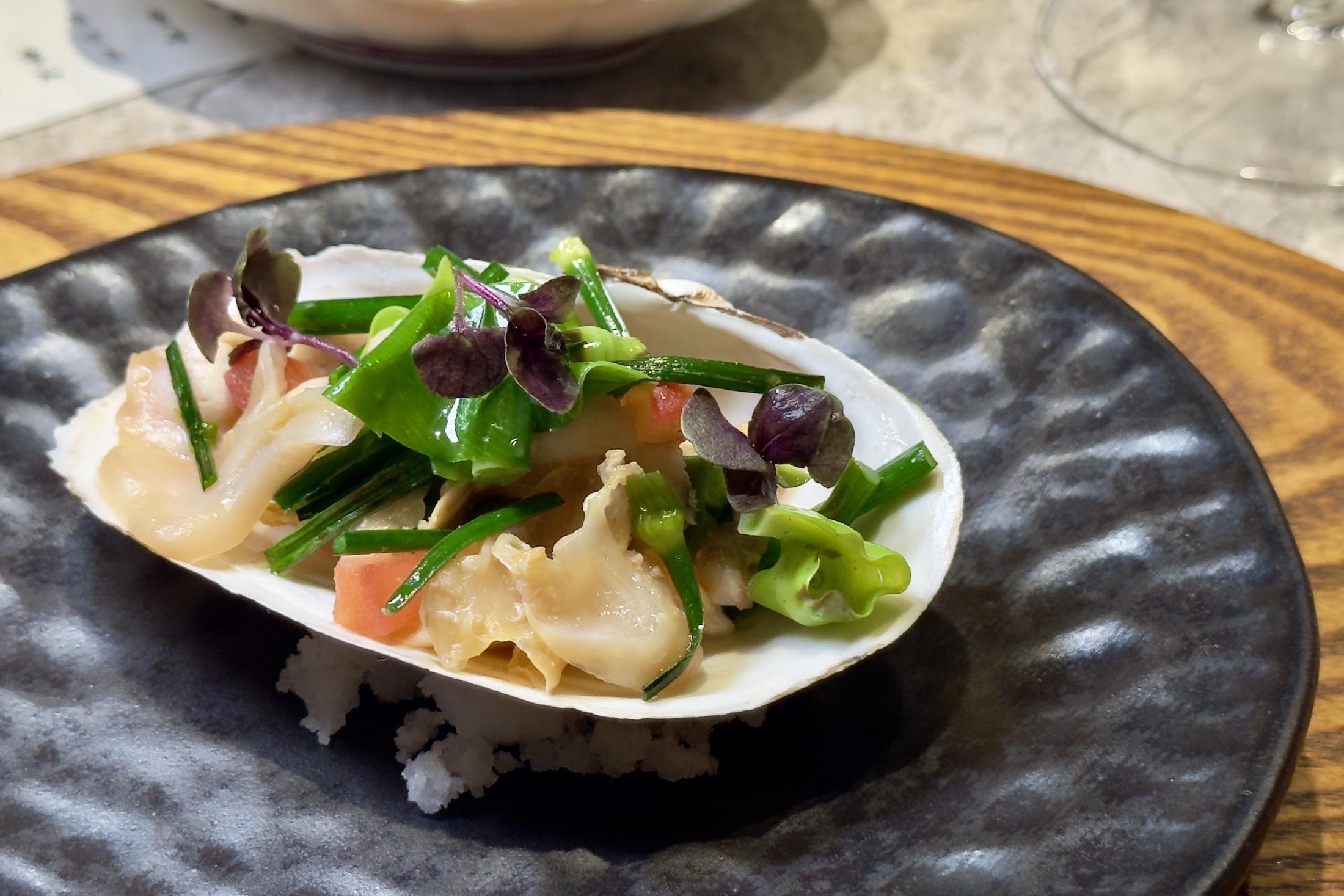 「海松貝」依不同部位分段料理,搭配番茄、韭菜花與山蘇收汁,凸顯鮮甜與彈嫩口感。