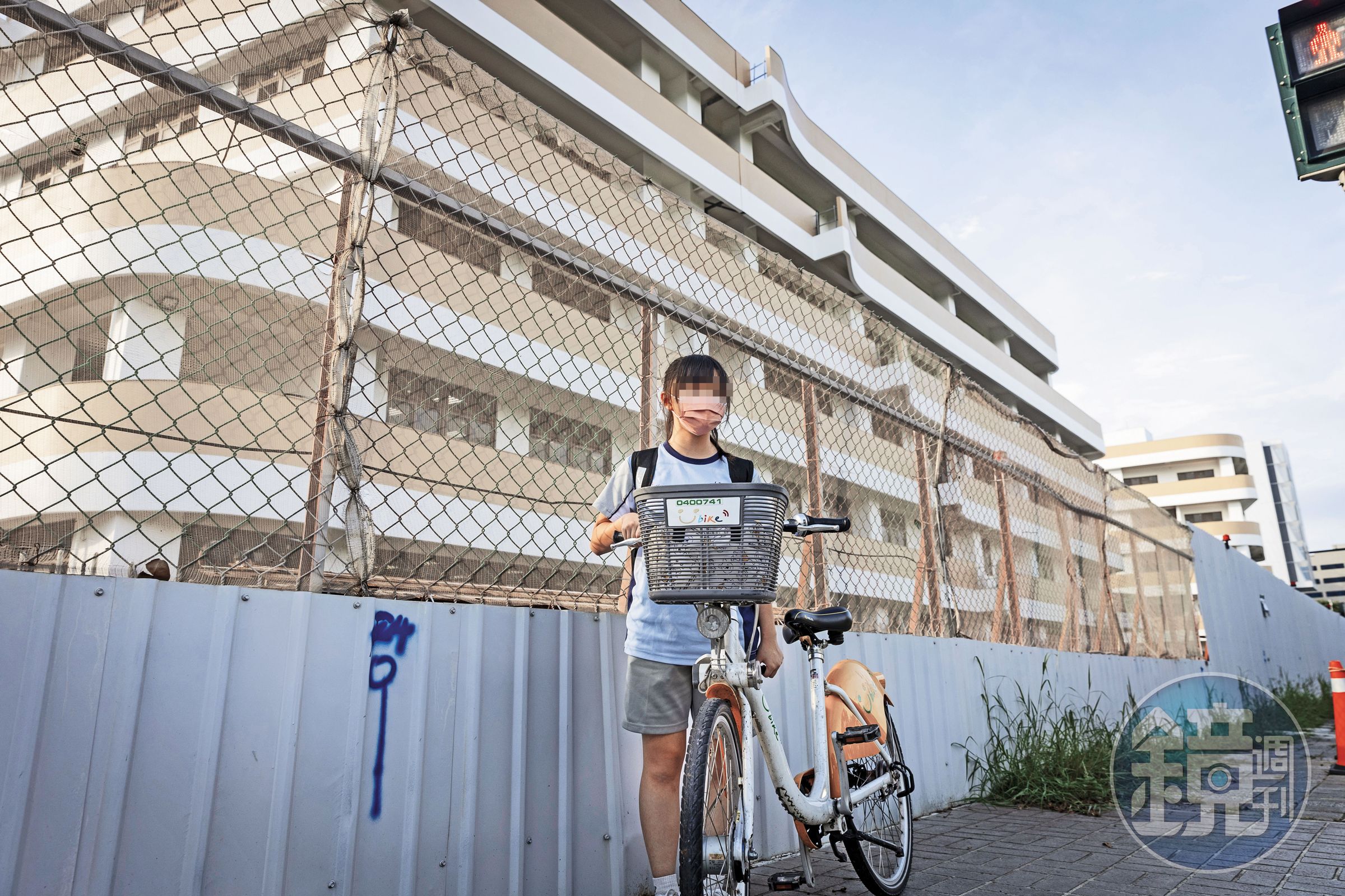 竹科地區人口激增，學校建設速度跟不上入學需求，許多新校在未完工狀態下即招生。圖為一名國中生放學行經學校外圍的工地圍籬。