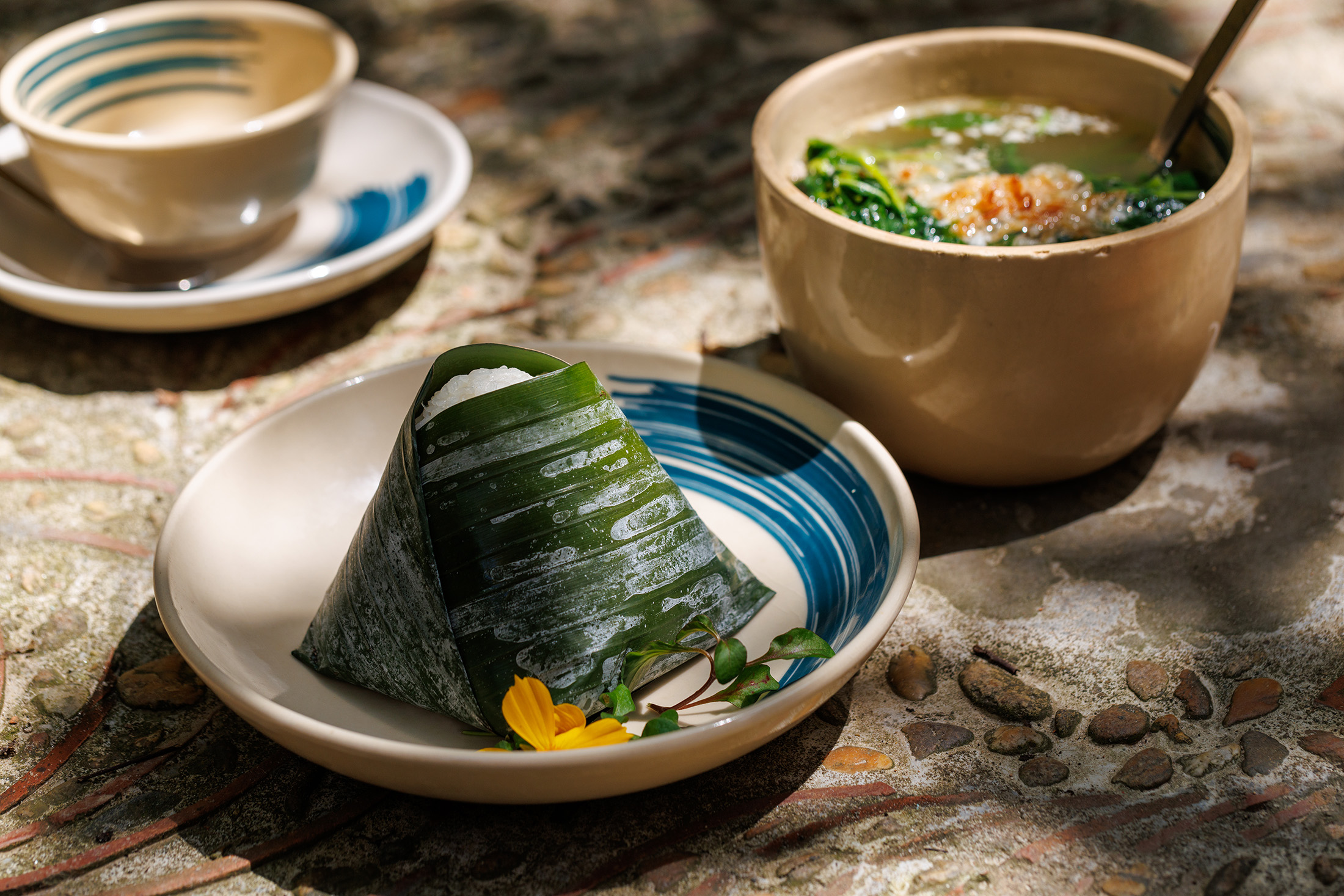 極具鄉村色彩的「芭蕉葉包飯」，將米飯與椰漿或香料拌勻，包在芭蕉葉中蒸煮出清新草香，拆開時香氣撲鼻。搭配茶桂村直送、清甜回甘的鮮綠蔬菜湯，是最道地的農家菜餚。