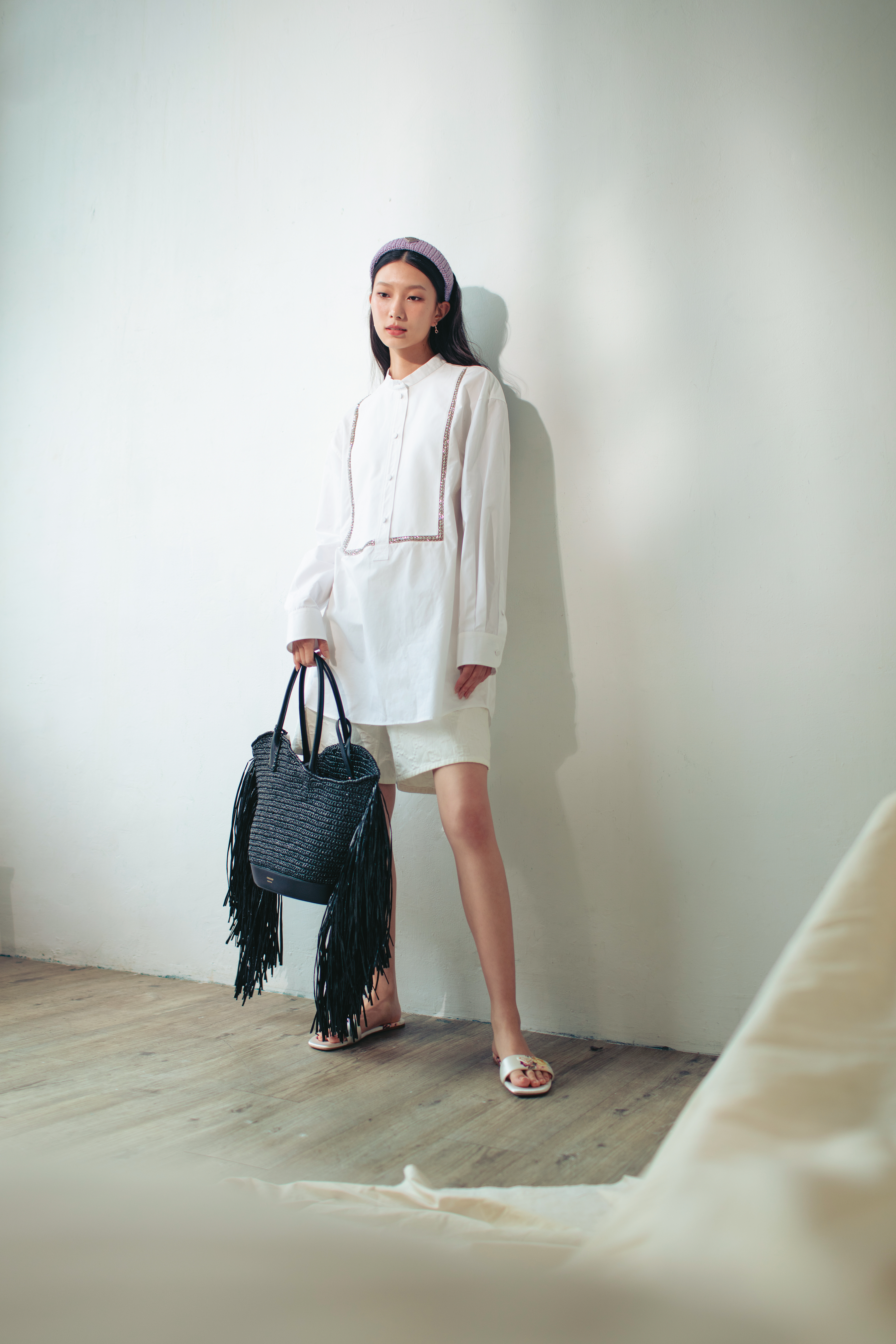 黑色流蘇Cut out編織手提包 NT$105,000 by FERRAGAMO／白色長袖開領水鑽襯衫 NT$89,000 by GUCCI／白色百慕達褲 NT$43,000 by GUCCI／花卉便鞋 價格店洽 by PRADA／鉤織髮箍 NT$20,000 by PRADA／18K金馬銜鍊耳環 NT$59,900 by GUCCI