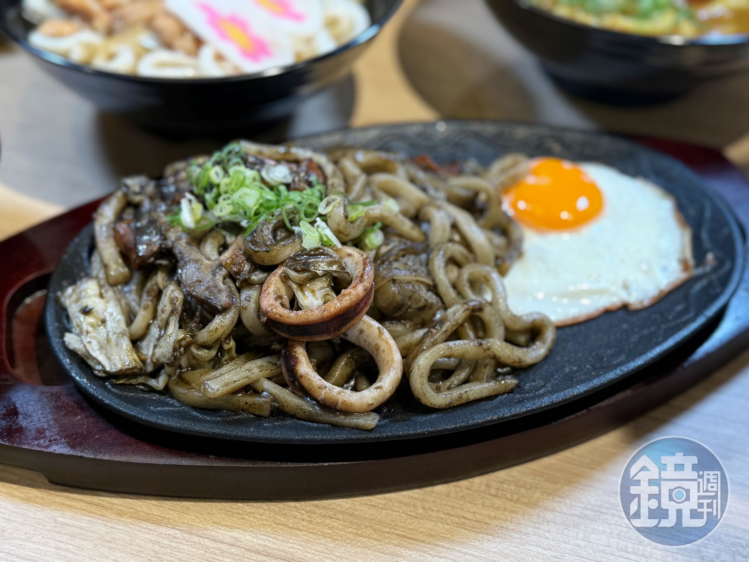 台灣限定的「烏賊墨炒烏龍麵」以滾燙鐵板盛裝,濃郁墨魚醬均勻包覆麵條,高溫快炒逼出十足鑊氣,Q彈有勁、越嚼越香。(250元/份)