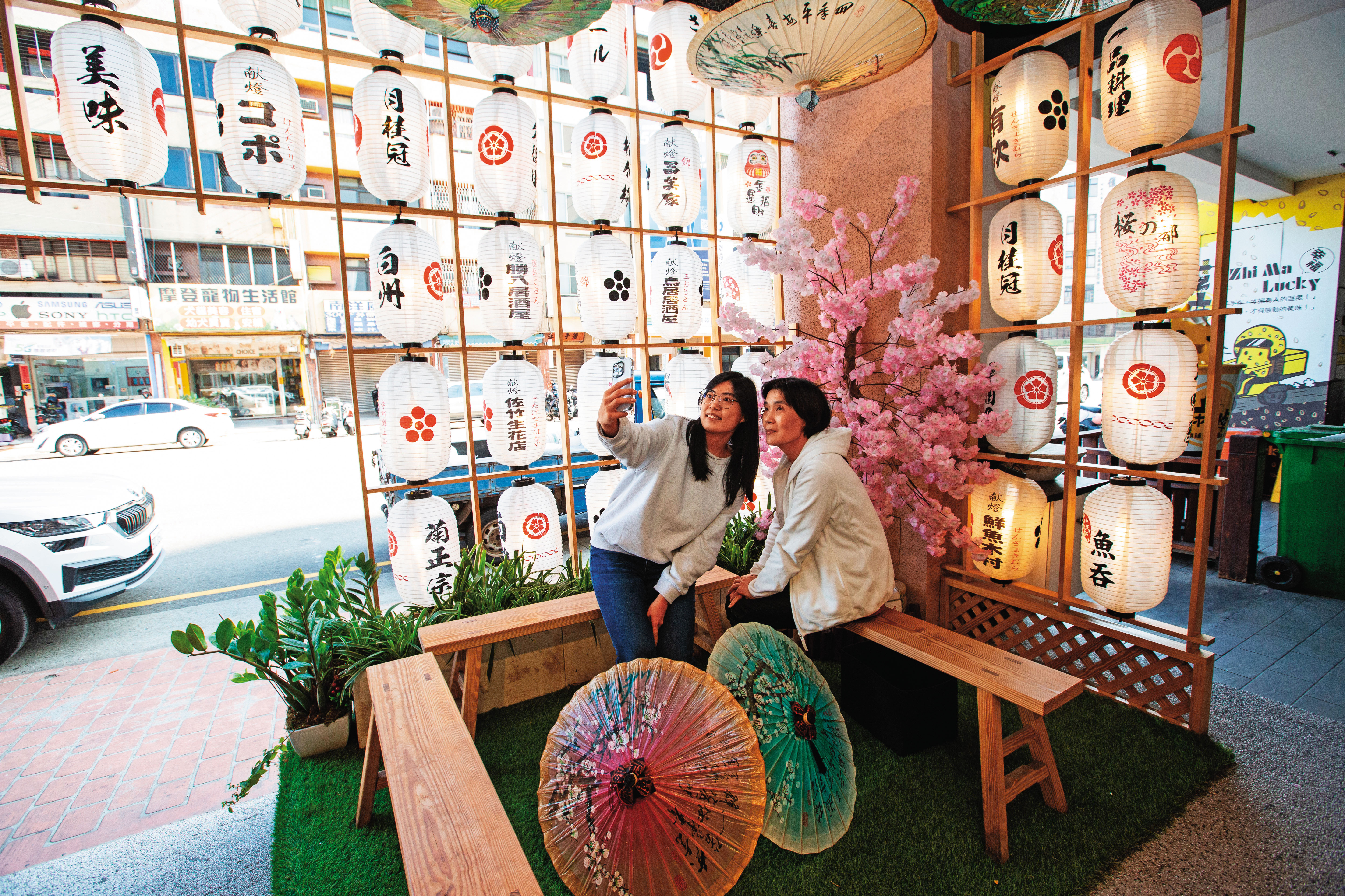 魚吞壽司店外候客區設計有美美的日式燈籠、美濃紙傘網美牆，吸引顧客拍照打卡。