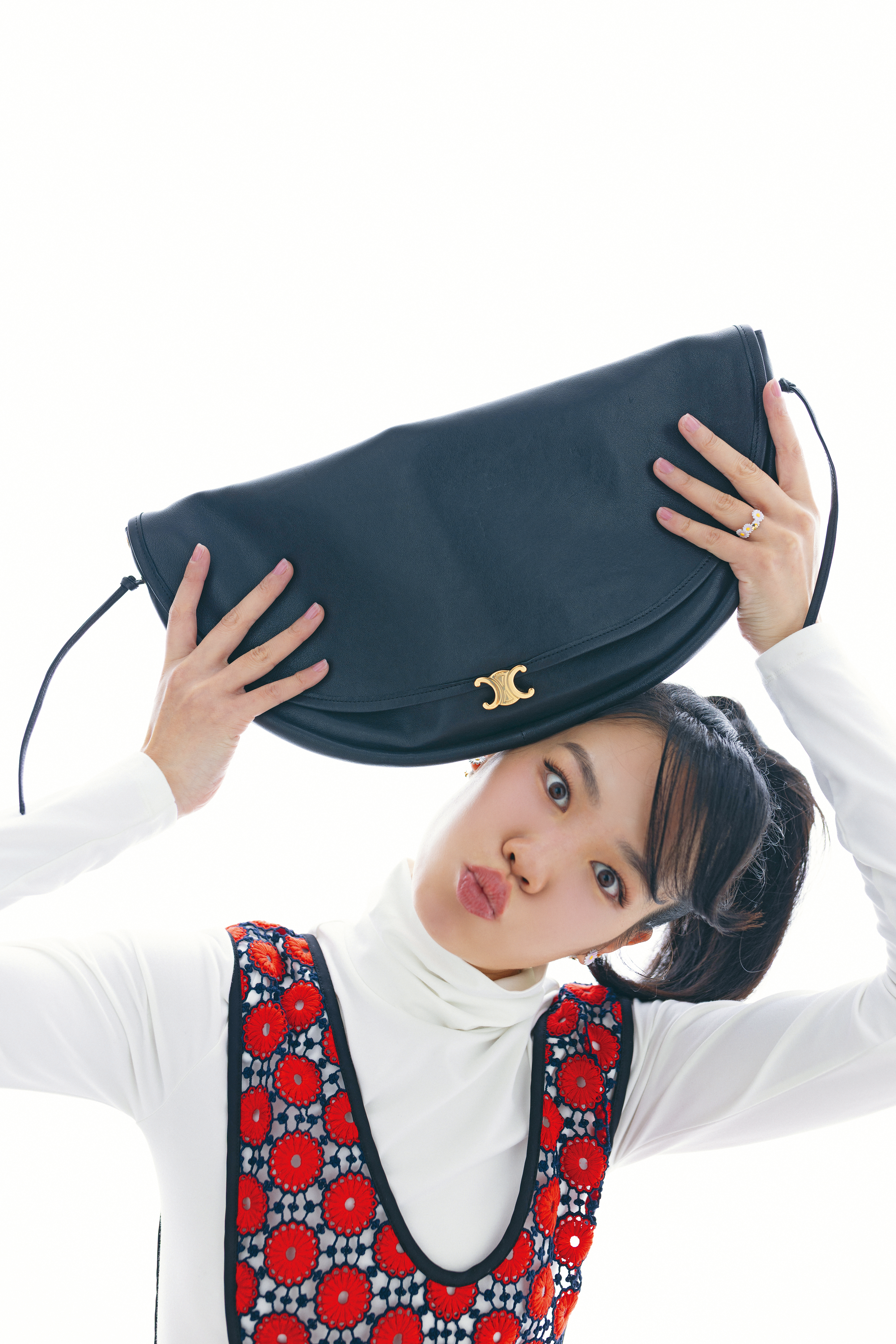白色高領上衣 NT$29,000 by CELINE、花卉裝飾圍裙 價格店洽by MIU MIU、雛菊耳環NT$19,000 by Dior、雛菊戒指 NT$18,000 by Dior、Halfmoon Soft Triumph亮澤羊皮革手袋 NT$110,000 by CELINE。
