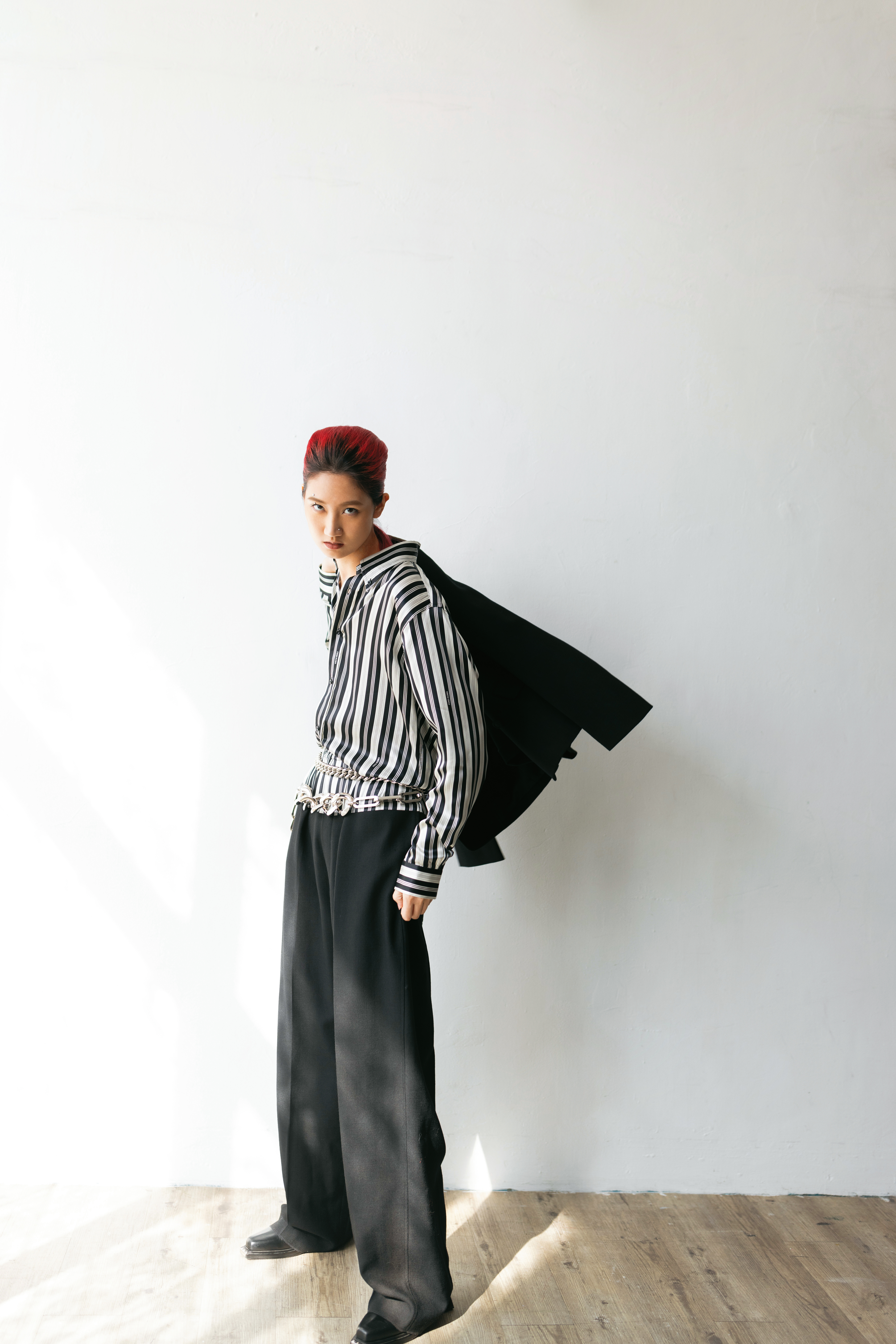 黑色西裝外套 NT$110,000 by FENDI；條紋襯衫 NT$55,200 by by FENDI；黑色寬褲 NT$55,200 by FENDI；黑色金屬裝飾切爾西靴 價格店洽 by SANDRO；銀色腰鍊 NT$75,700 by GUCCI。