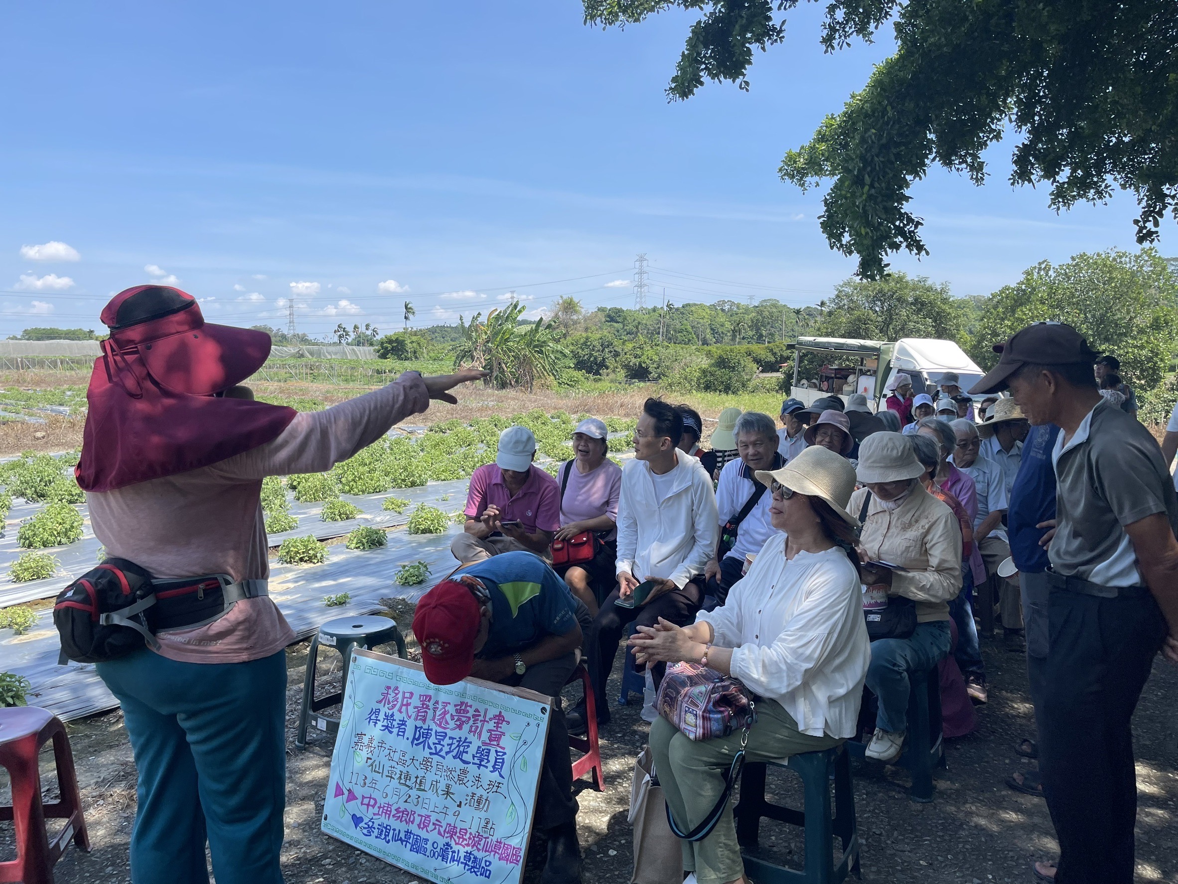 受獎人陳昱璇(左一)在仙草田旁向民眾推廣其種植仙草的理念。(移民署提供)