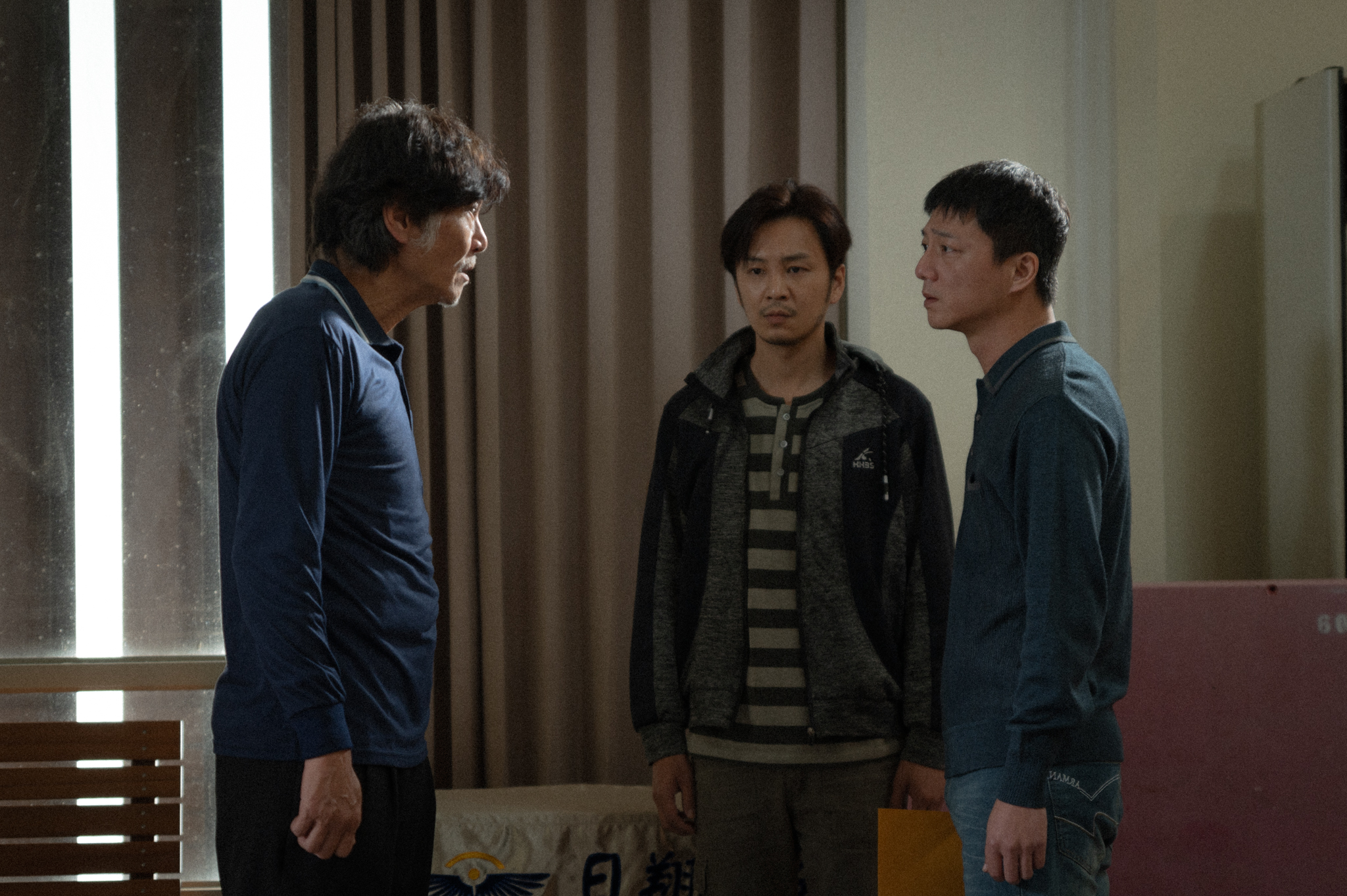 《春行》講述台灣傳統家庭關係以及同志伴侶所面對的困境，圖為喜翔（左）在喪妻之後，和藍葦華（右）飾演的兒子與張書偉（中）飾演的兒子伴侶在商討後事。（今日影像藝術提供）