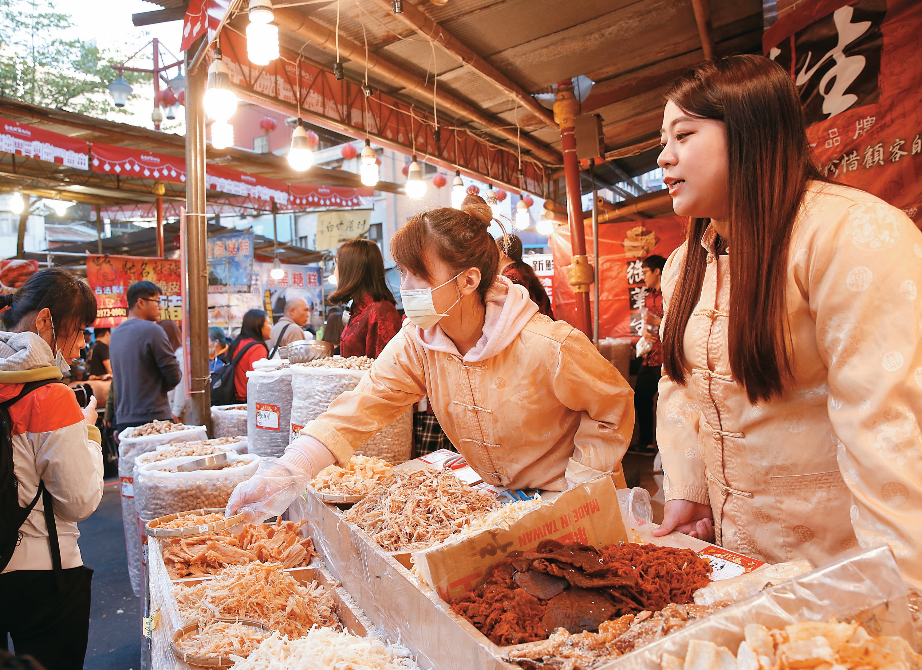 台北年貨大街攤商熱絡招呼顧客，沿街洋溢年節熱鬧氣氛。（資料照／楊彩成）