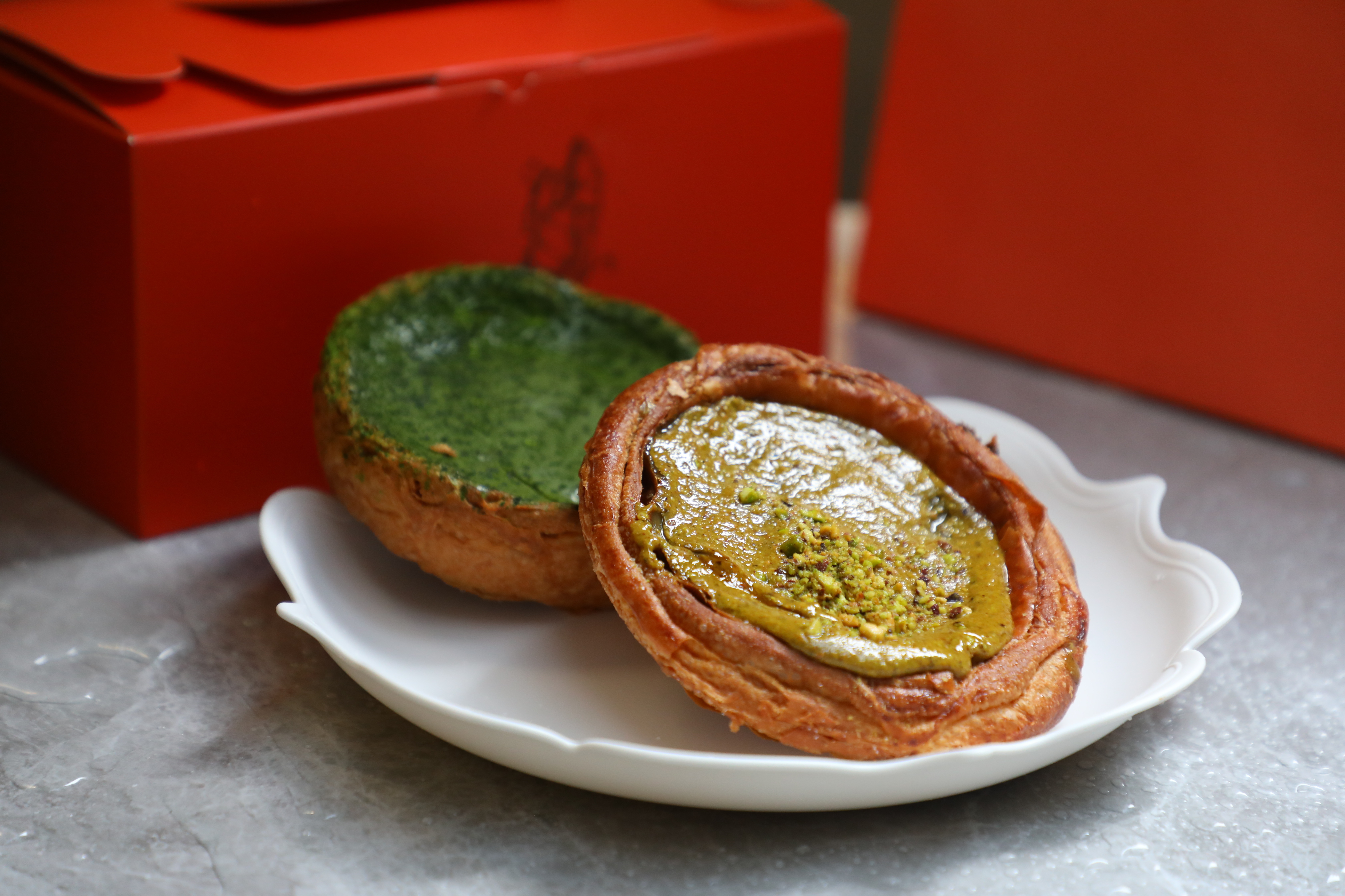 會流漿的濃郁開心果丹麥酥「Pistachio custard danish」（前，港幣68元／個，NT$279）與苦甜口味有麻糬夾心的「Matcha Mochi custard danish」（後，港幣60元／個，NT$246）都是熱賣商品。