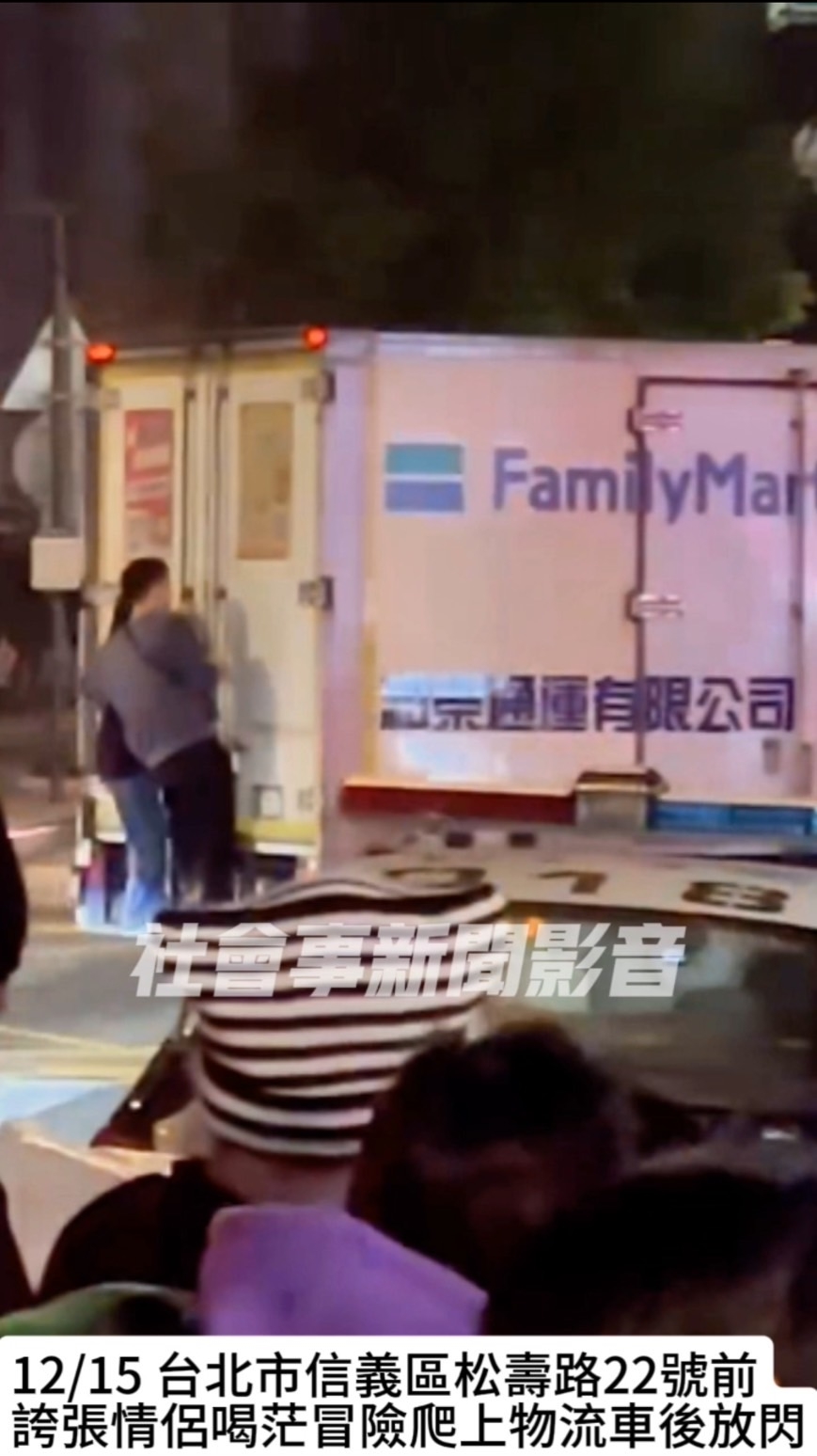 情侶站在貨車後方車斗橫桿上,不時親吻放閃。(翻攝自社會事新聞影音)