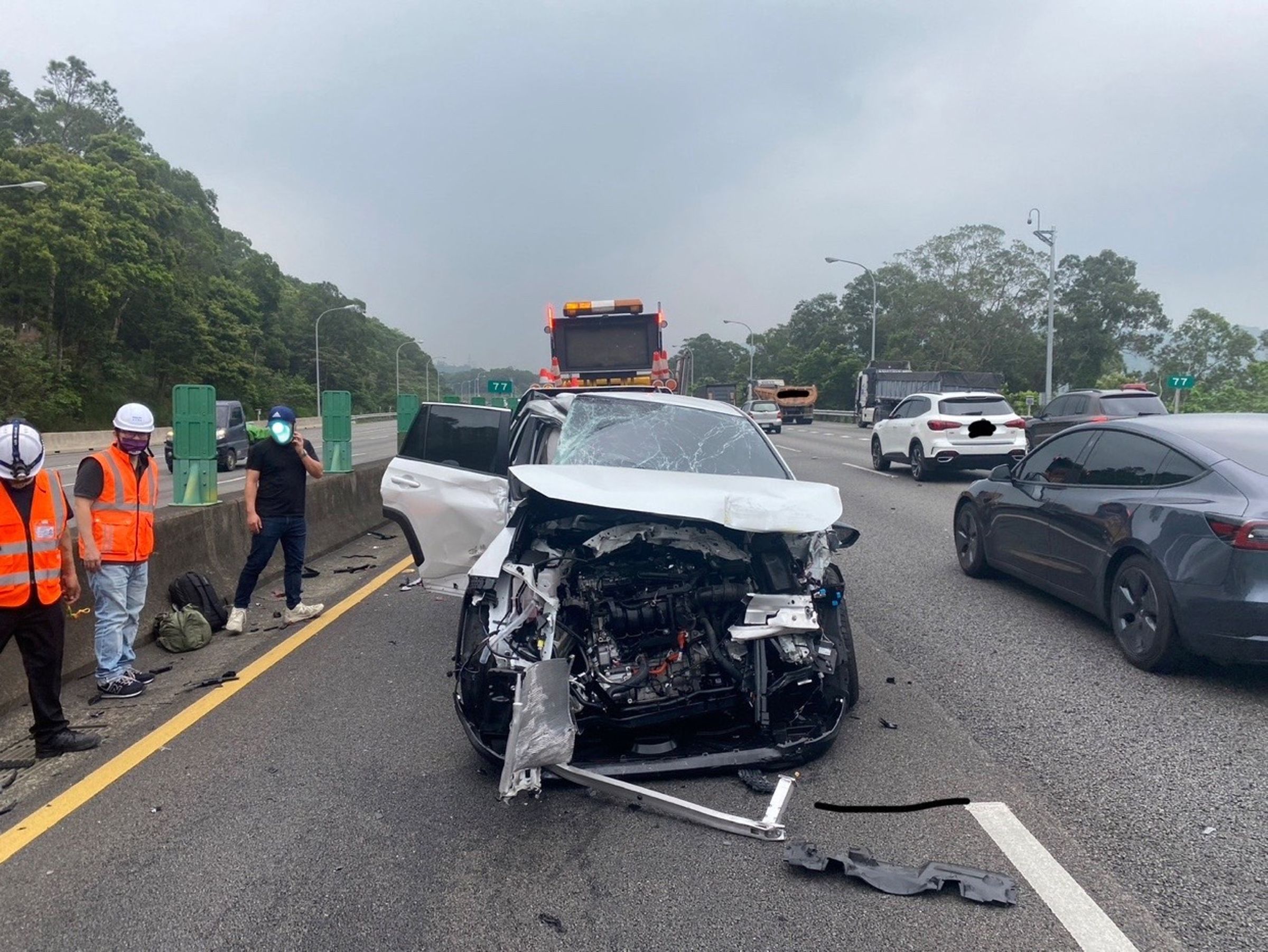 白色轎車駕駛因開啟輔助駕駛系統未注意車前狀況而撞上緩衝車,車頭幾乎全毀。(翻攝畫面)