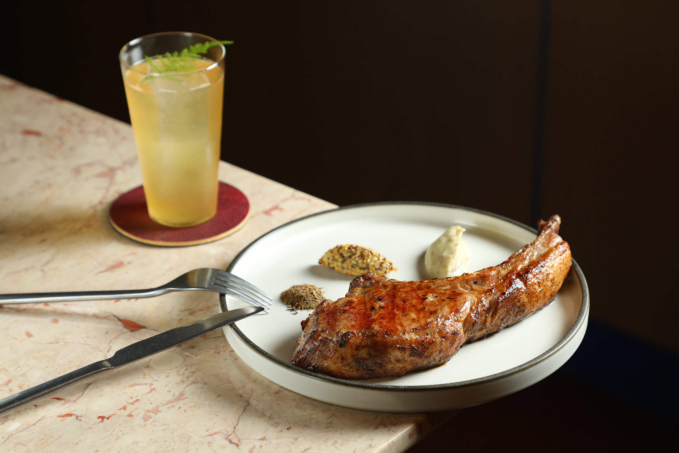 Ochre Grill & Bar 的「熟成帶骨巧克力豬」在炭火炙烤下,使熟成豬肉的香氣與油脂豐腴完全釋放,沾上甜、辣、鹹3種風味調料,更增加品嘗趣味。(1,380元/份)