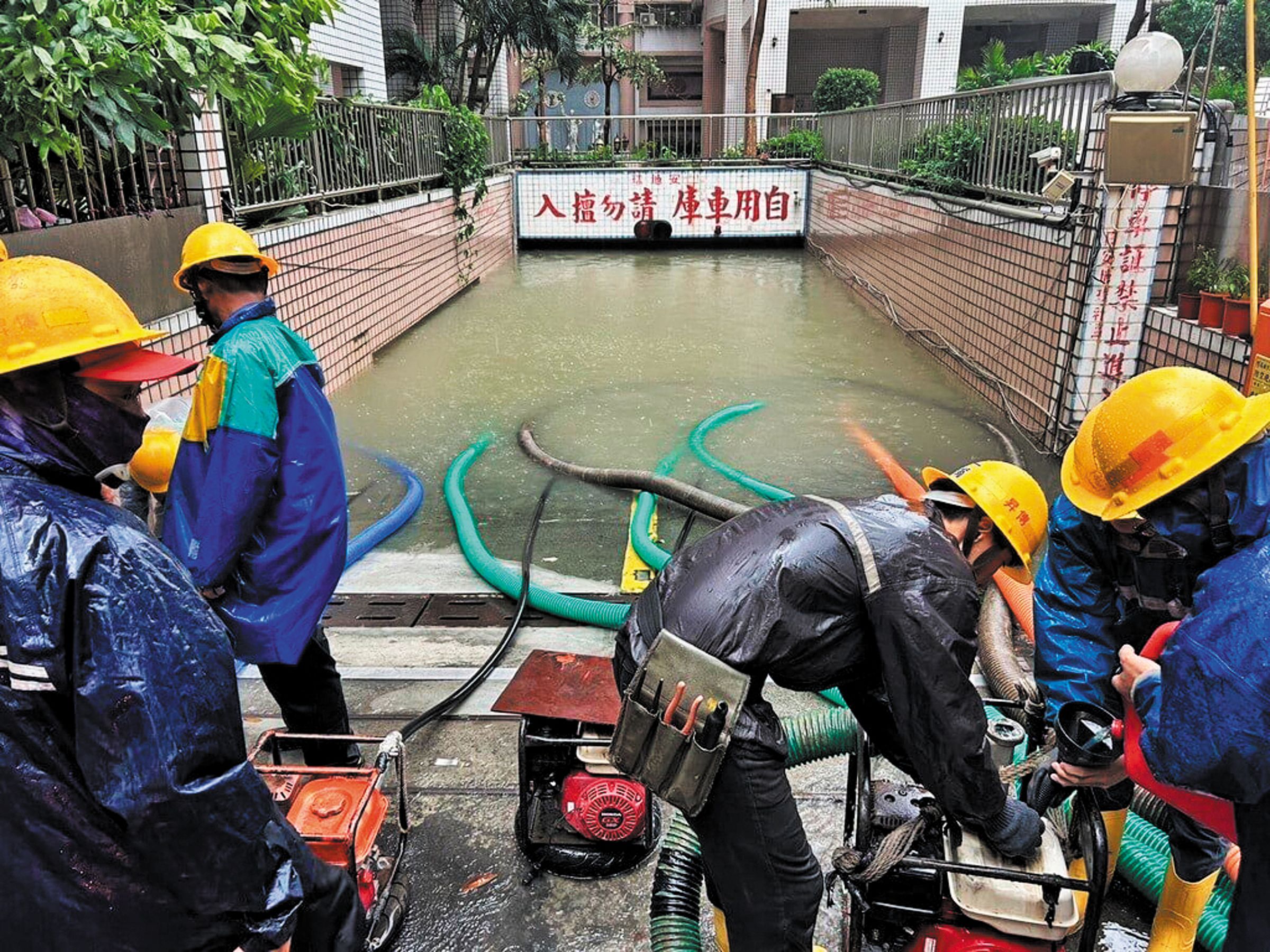 高雄一處民宅地下停車場大淹水,工程人員動用大型機具抽水。(台電提供)