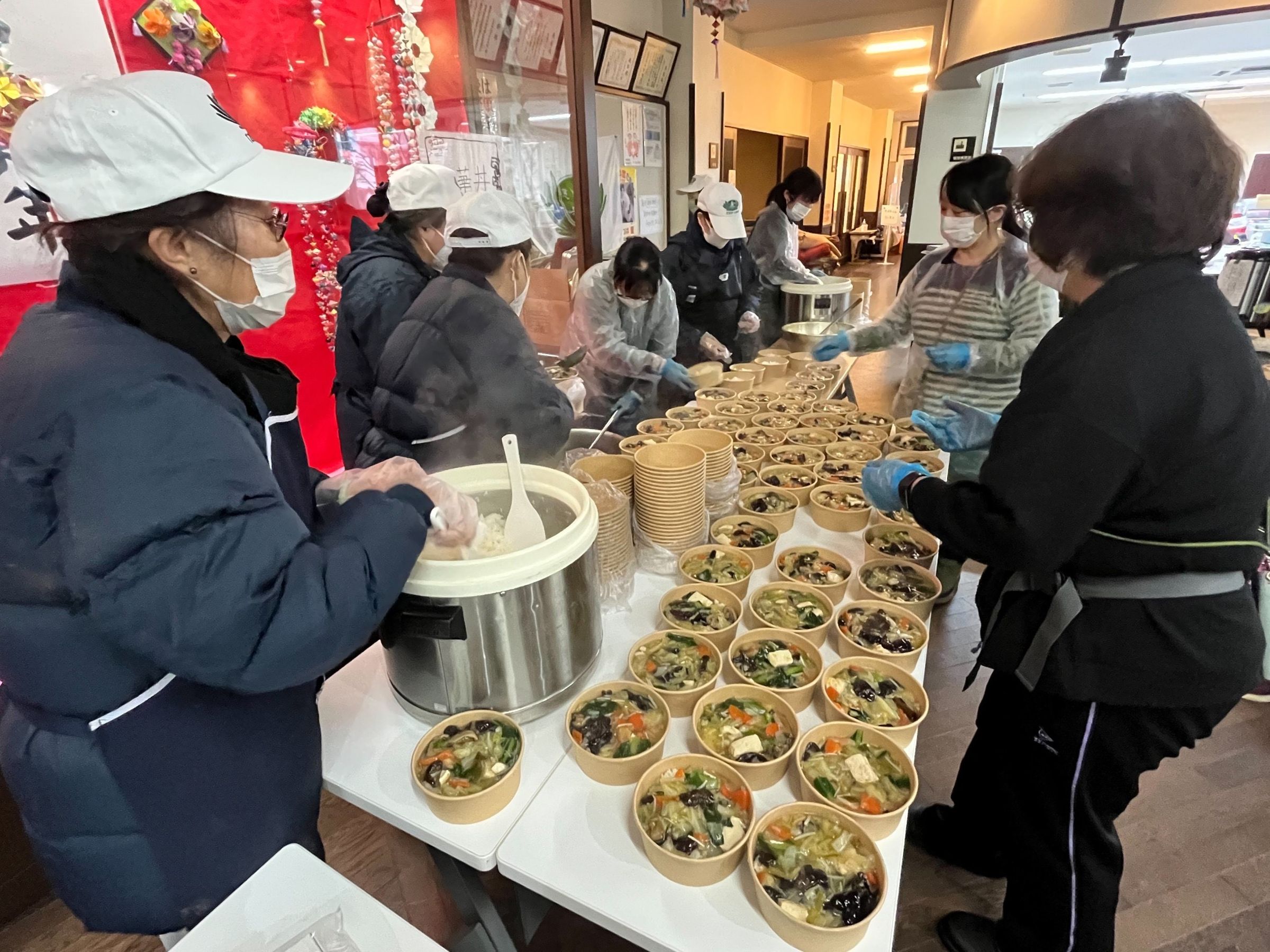 慈濟志工深入災區，在寒雪中為暫居避難所的長者準備熱食。（慈濟基金會提供）
