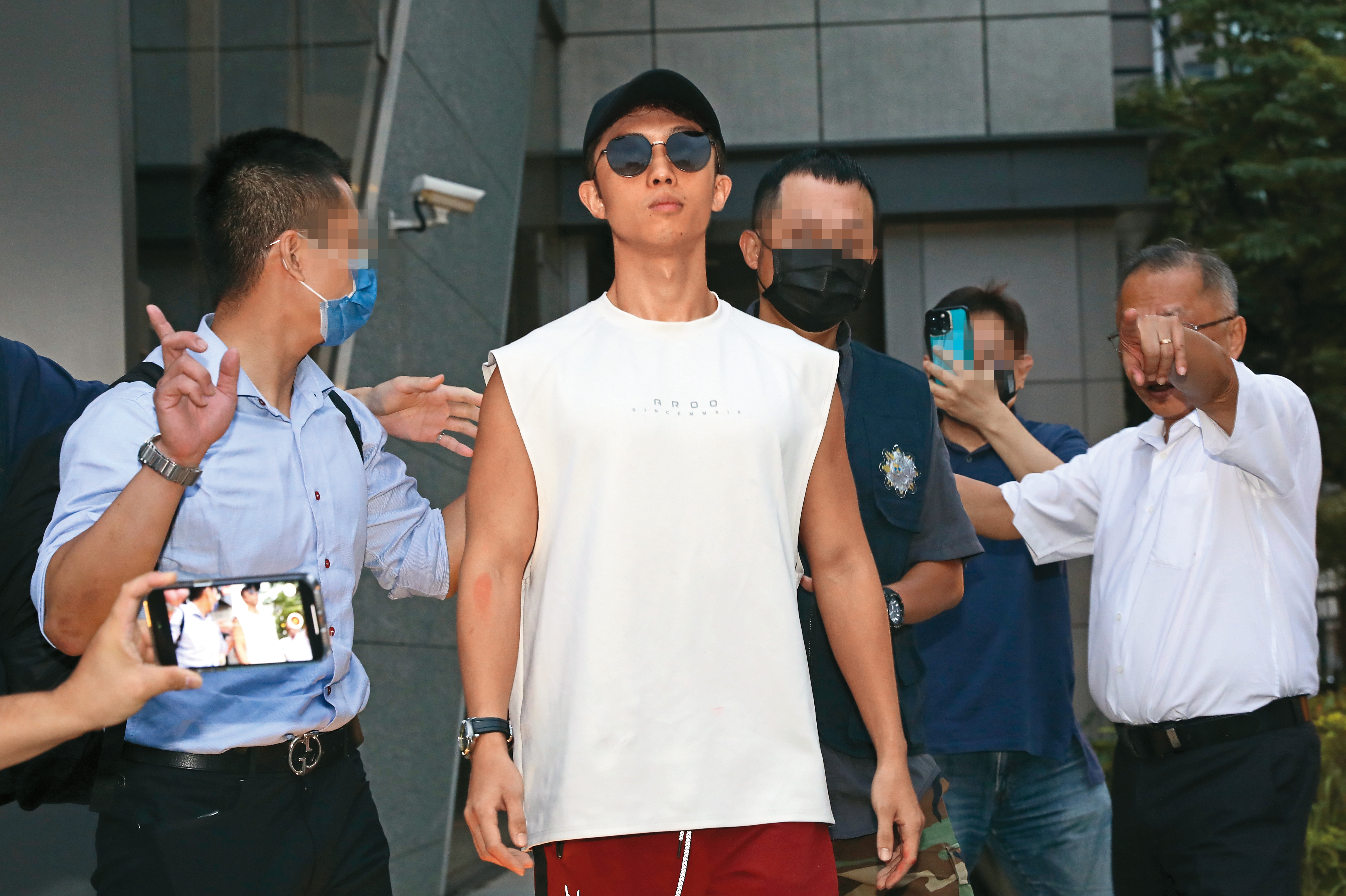 孫安佐（左2）從北市刑大帶出移送北檢，他因攜帶瓦斯火槍在北市信義區的夜店外進行實測，引起群眾圍觀議論。警方隨後介入調查，發動搜索行動，在孫鵬家中查扣疑似火藥的粉末、刀械以及瓦斯火槍等物品。