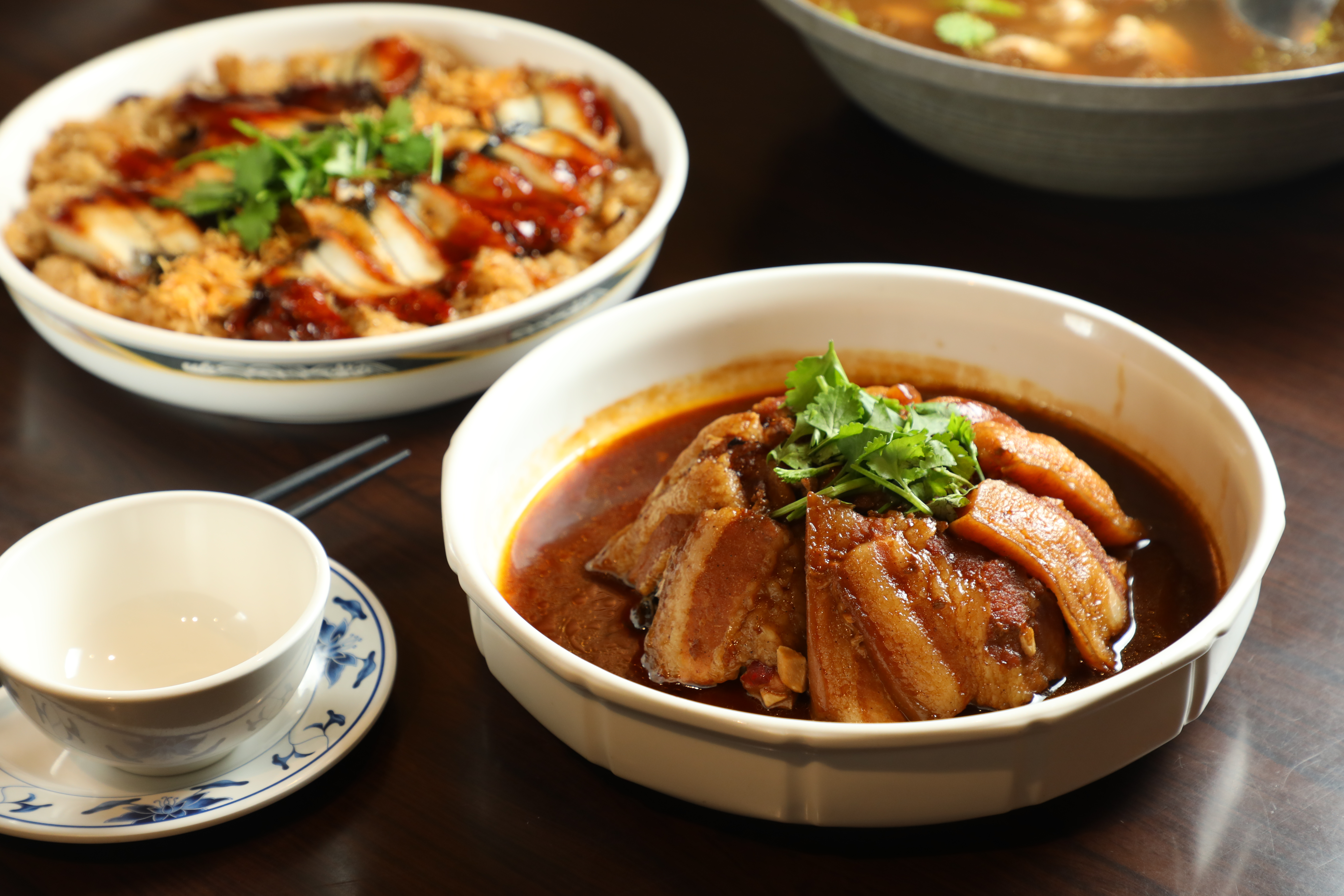 大烹小饌的「梅香古早扣方」（前，年菜980元／份）將三層肉炸出虎皮再去蒸，美味秘訣是分兩次蒸煮入味；搭配以黑麻油拌炒油飯的「黑麻油鰻貝御飯」（後，年菜980元／份）。