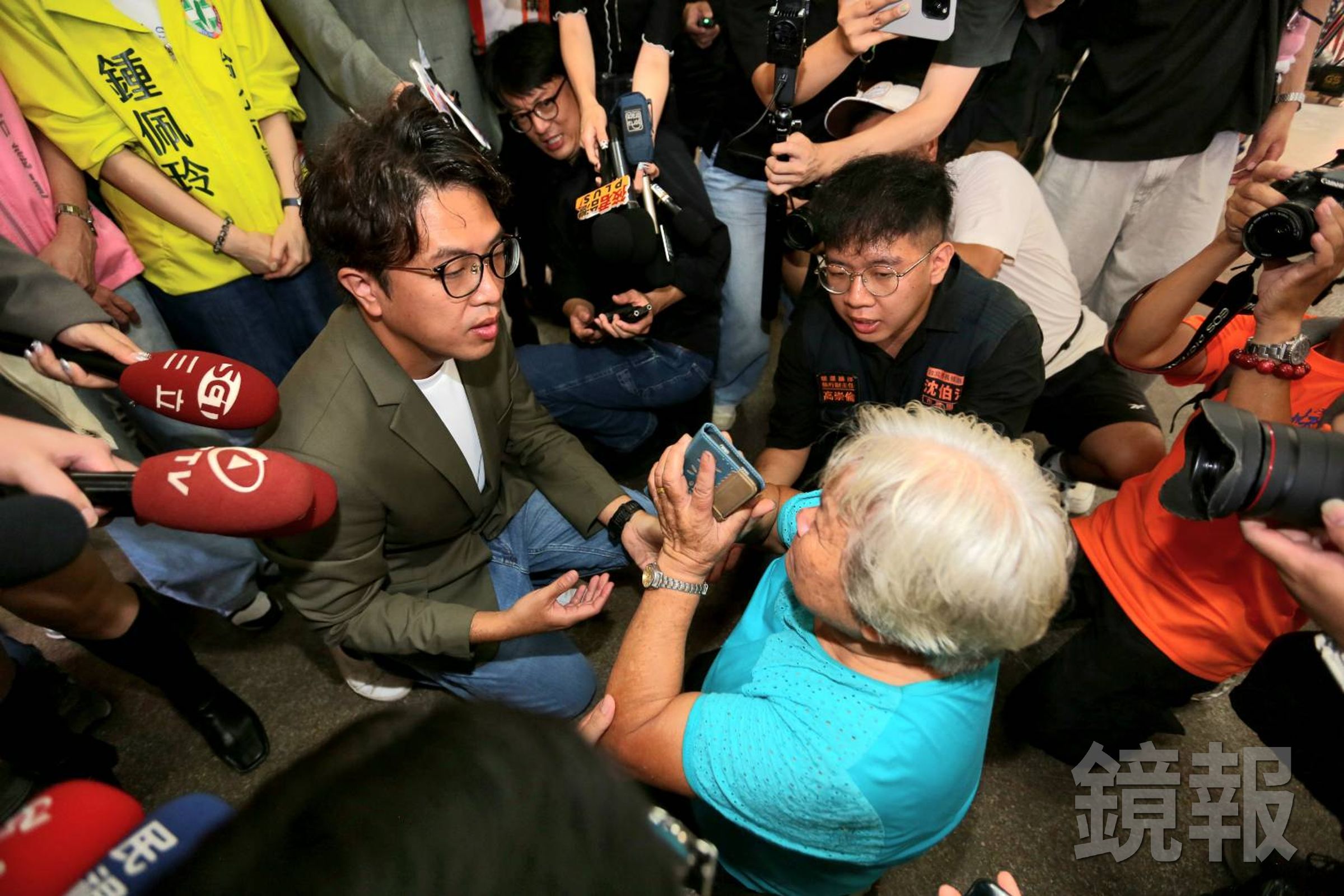婦人激動下跪陳情,沈伯洋連忙上前蹲下安撫。(鏡報姜永年)