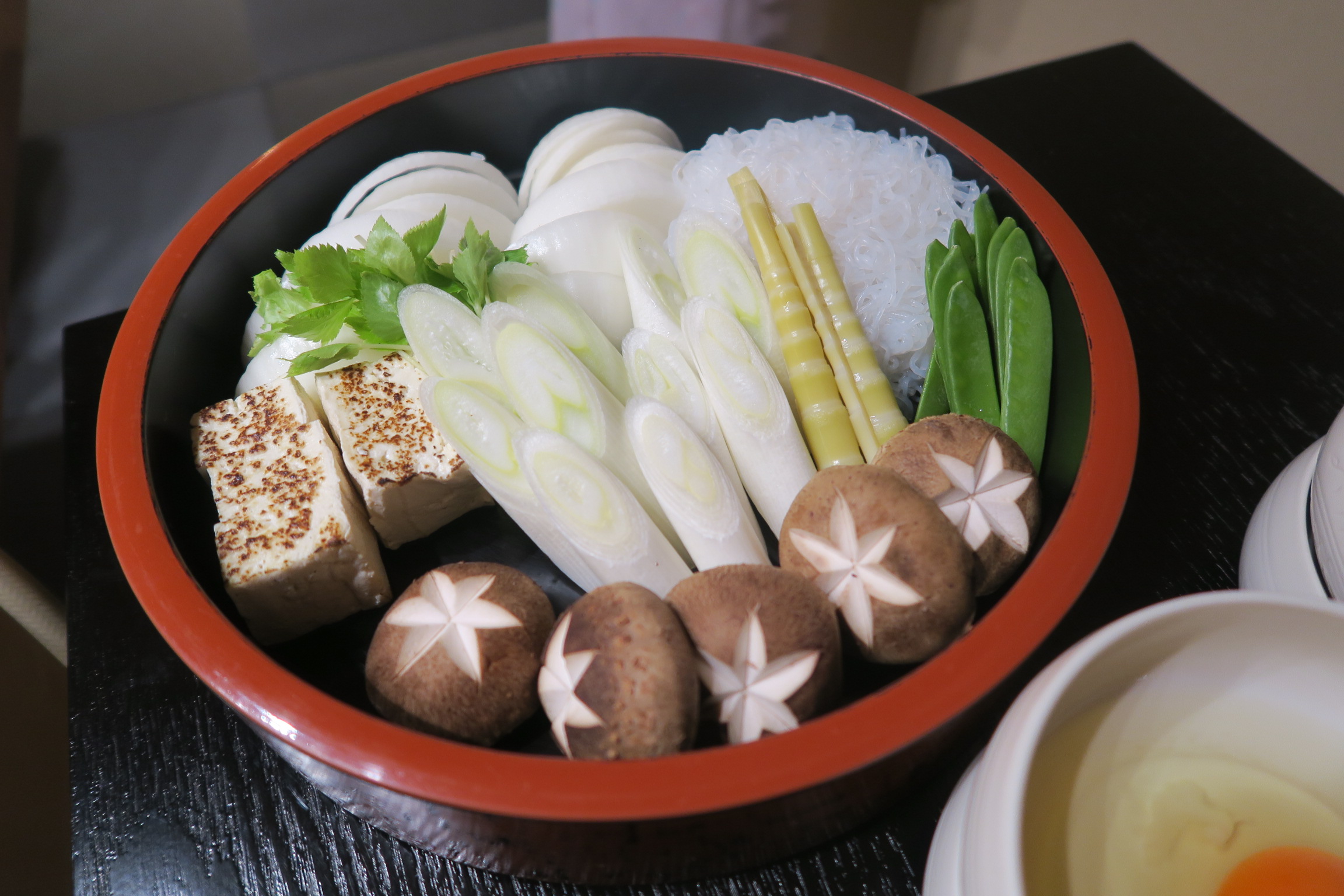 菜盤包括香菇、大蔥、蒟蒻、洋蔥、燒豆腐等壽喜燒常見食材。