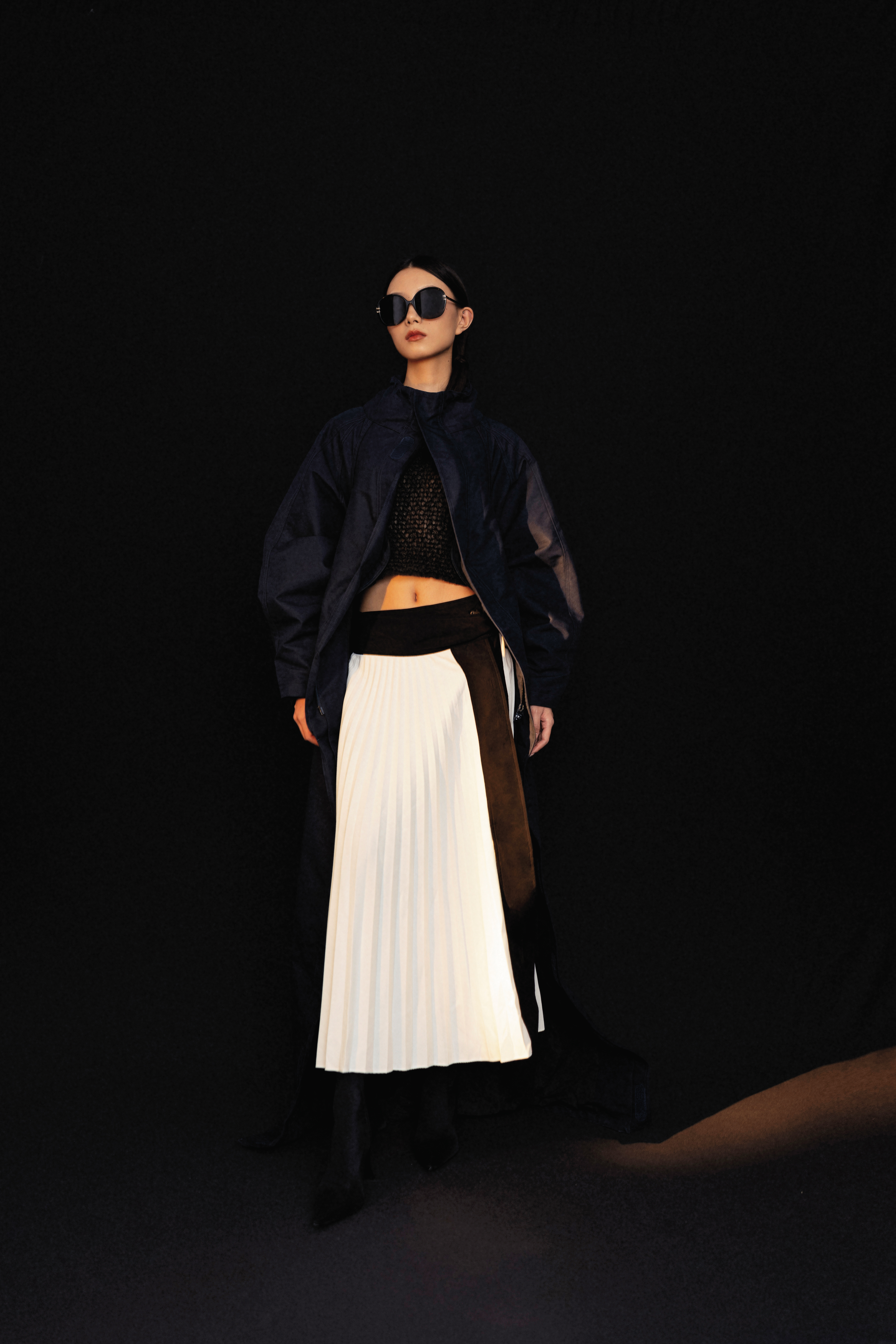 藍色派克大衣 NT$138,000 by BALENCIAGA，針織上衣 價格店洽 by CELINE BY HEDI SLIMANE，蝴蝶結細節褶襉裹式半截裙 NT$99,500 by LOUIS VUITTON，黑色襪靴 NT$63,800 by BALENCIAGA，Havana黑色墨鏡 NT$16,000 by Chloé。