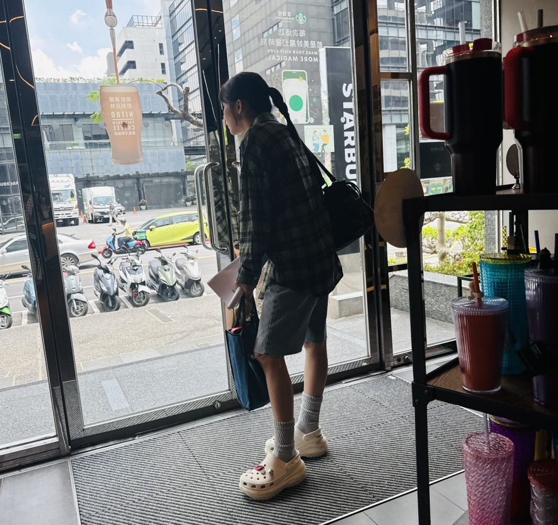 林萱瑜邊等咖啡邊探頭看門外。(讀者提供)