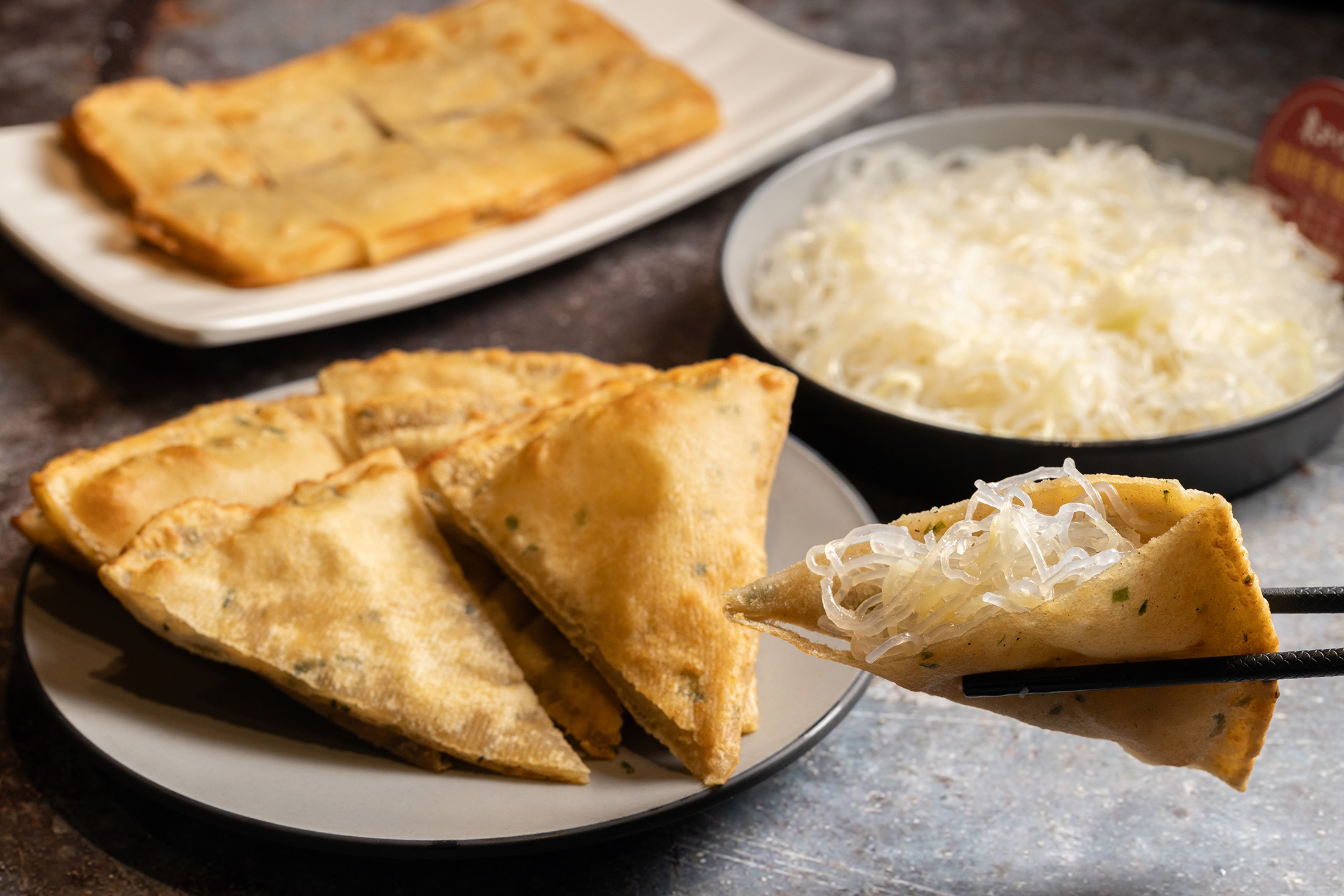店家自製的「蔥油餅」（前，50元／份）與「涼拌冬粉絲」（後，60元／份）都是人氣外帶小菜。