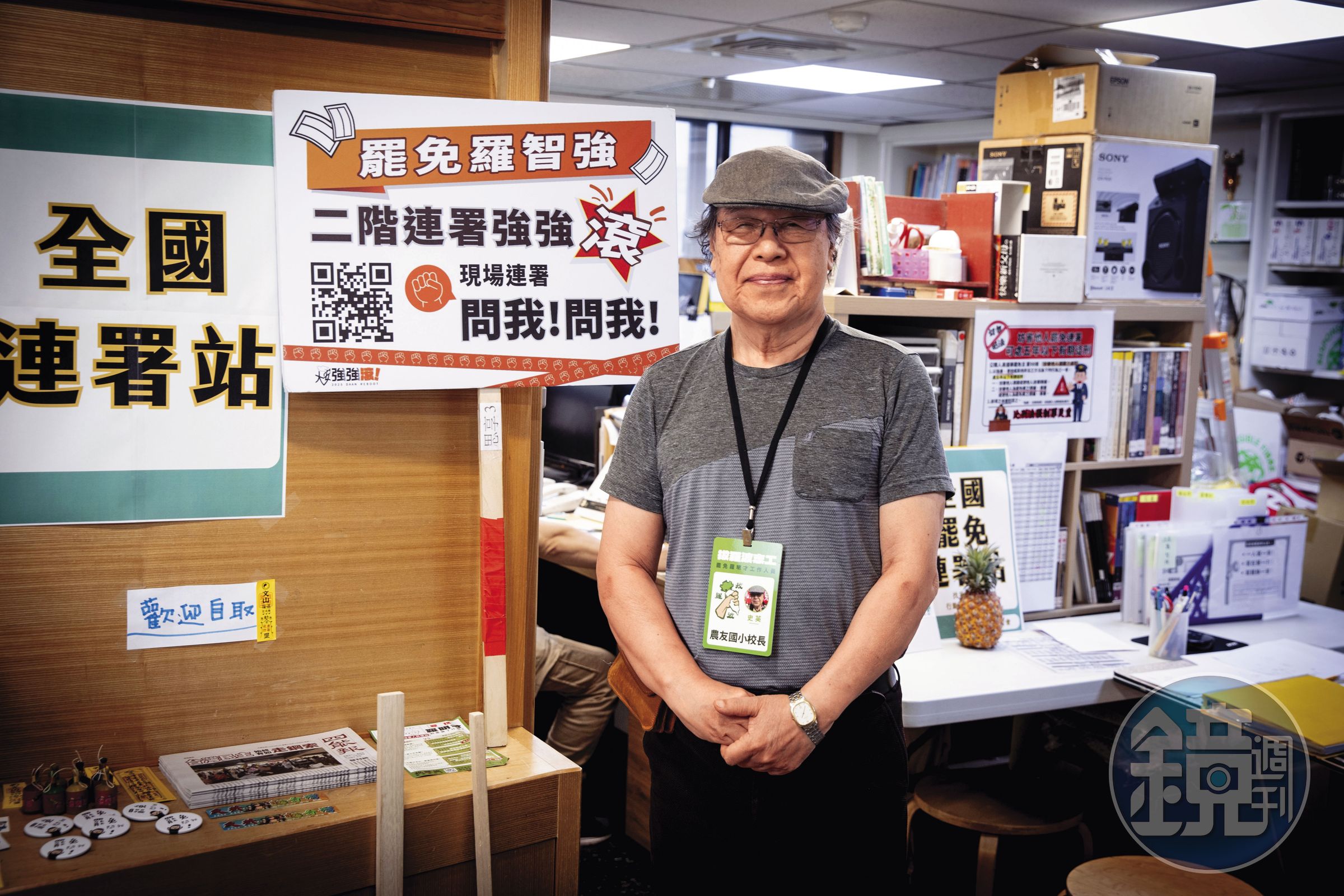 人本教育基金會門口擺滿各類創意貼紙、文宣。圖為史英在台北人本辦公室接受訪談，胸前掛著罷免羅明才的拔羅波志工名牌。
