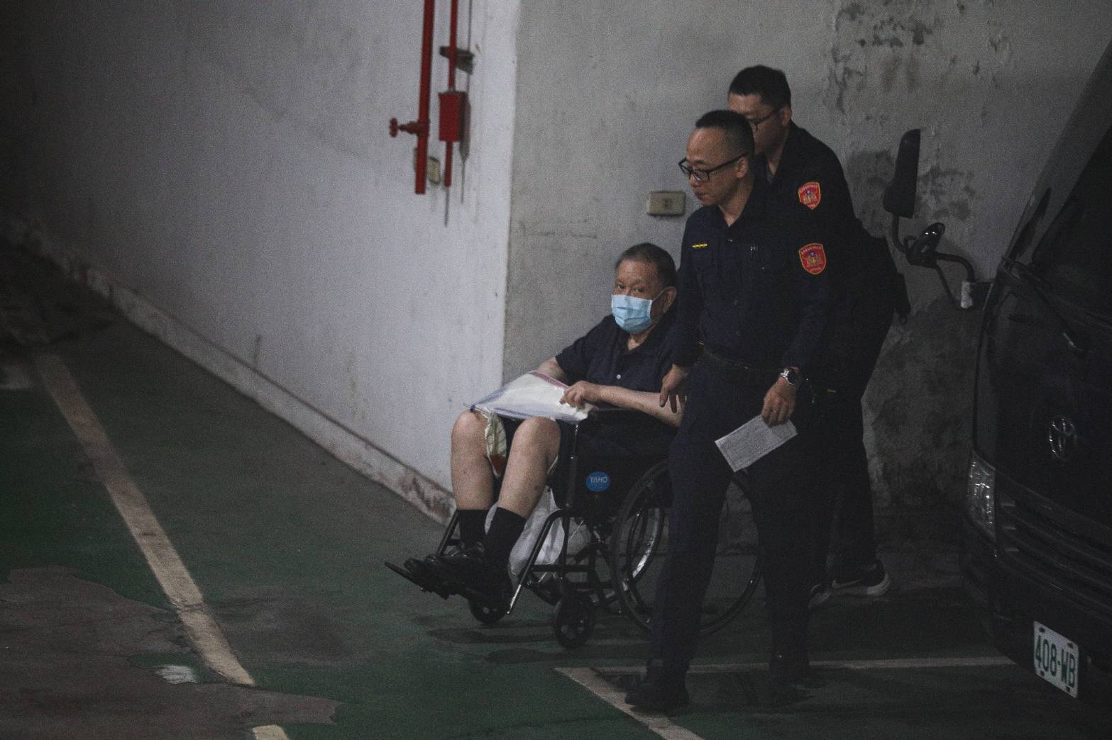 沈慶京住院2週後首次提訊，坐輪椅還看向鏡頭。