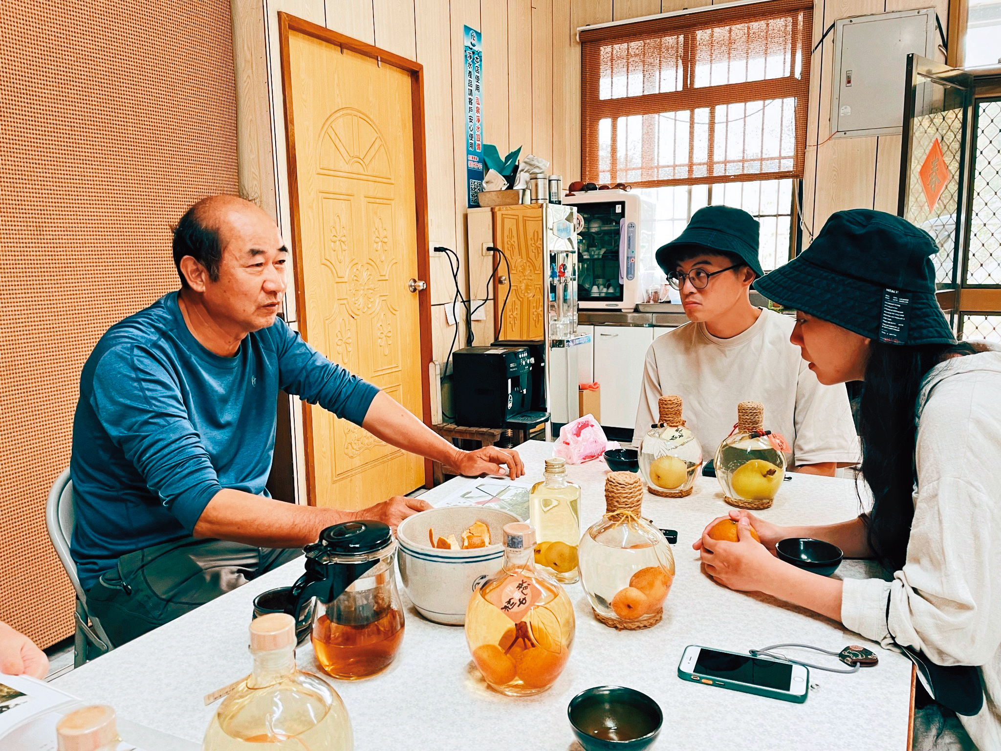 何安妘（右一）以台中東榮農場老闆蘇光明（左一）製作「瓶中梨」的甘苦，轉化成帶有奇幻風格的作品〈酒是機率—永不分離的機率〉。右二為繪製〈酒是遺憾—黑米糰子與酒〉的漫畫家錢君銜。（聚場文化提供）