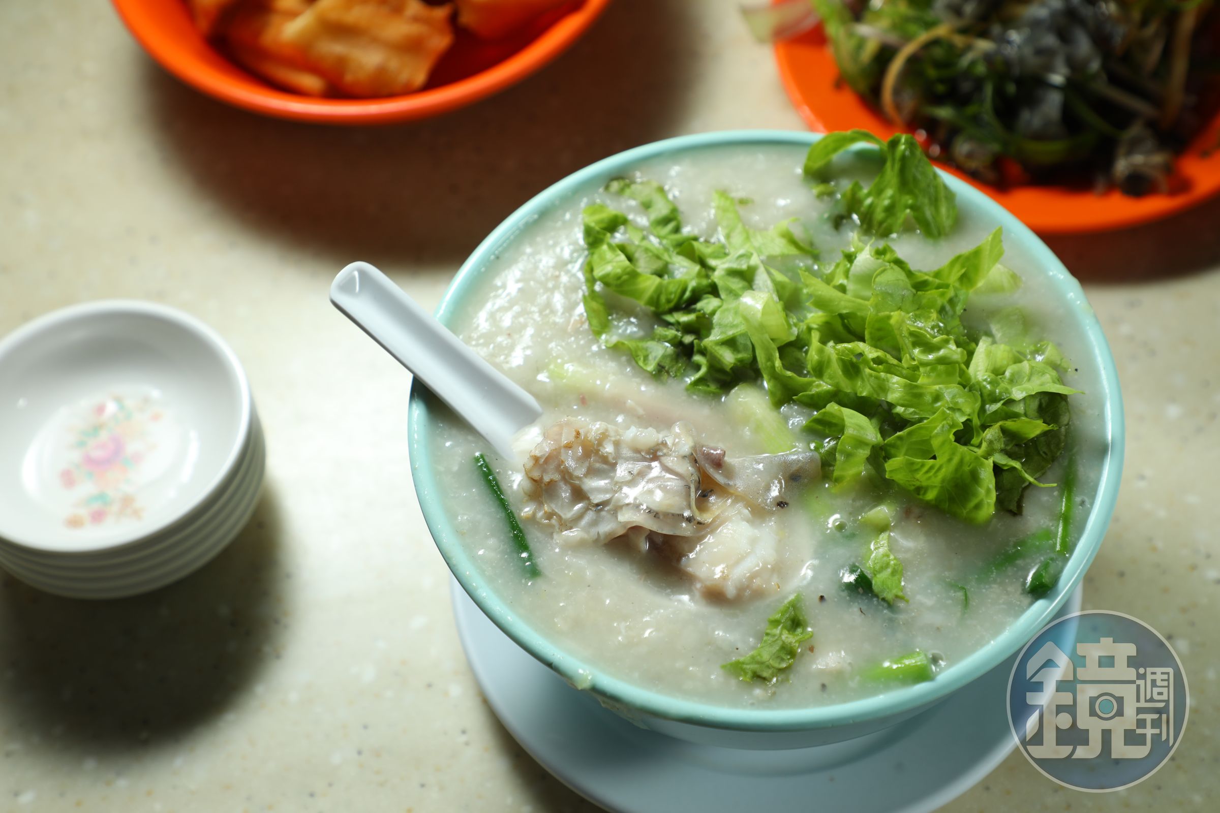 「魚腩粥」（前，港幣50元／碗）的粥面鋪滿生菜，能嘗到軟嫩魚肚，也可加點「油條」（後，港幣11元／份）來搭配。