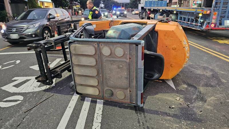 聯結車載運巨型堆高機竟在行駛中突然傾倒滾落。（屏東警分局提供）