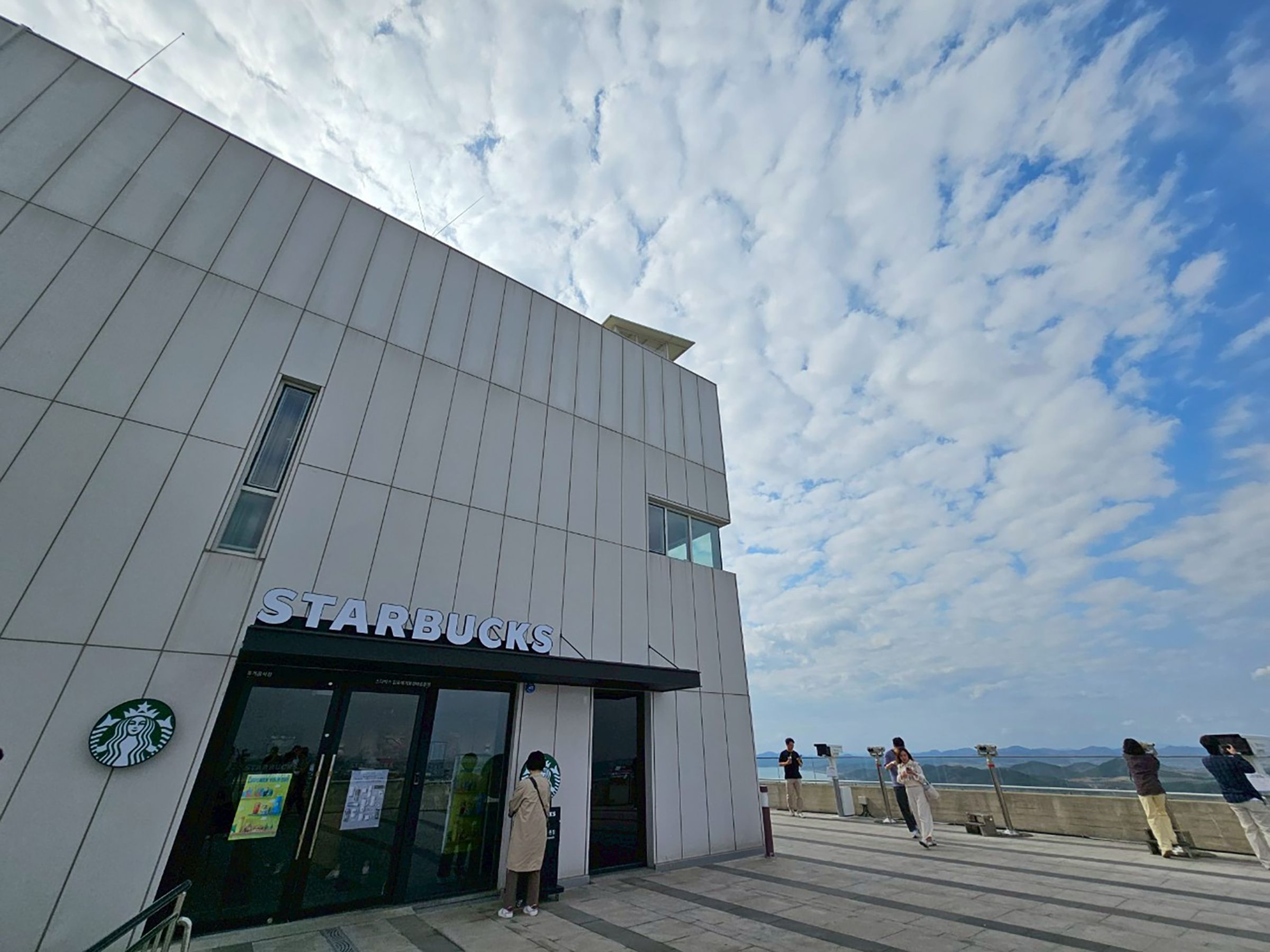 來到全球唯一的星巴克DMZ門市，手捧咖啡，窗外即是北韓的田野。（京畿觀光公社提供）