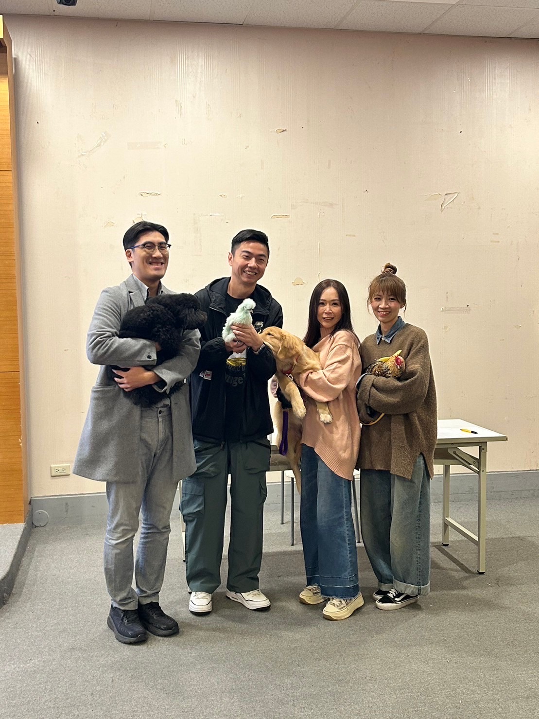 台北海大國合長林威克（左一）盛讚熊爸（左二）寵物行為訓練很受歡迎，右為寵物系主任王宥婷、課指組組長莊雅雯。有趣的是，拍照時，主任抱的狗正含著熊爸手上雞的腳，眾人笑說狗在吃雞腳凍了。（台北海大提供）