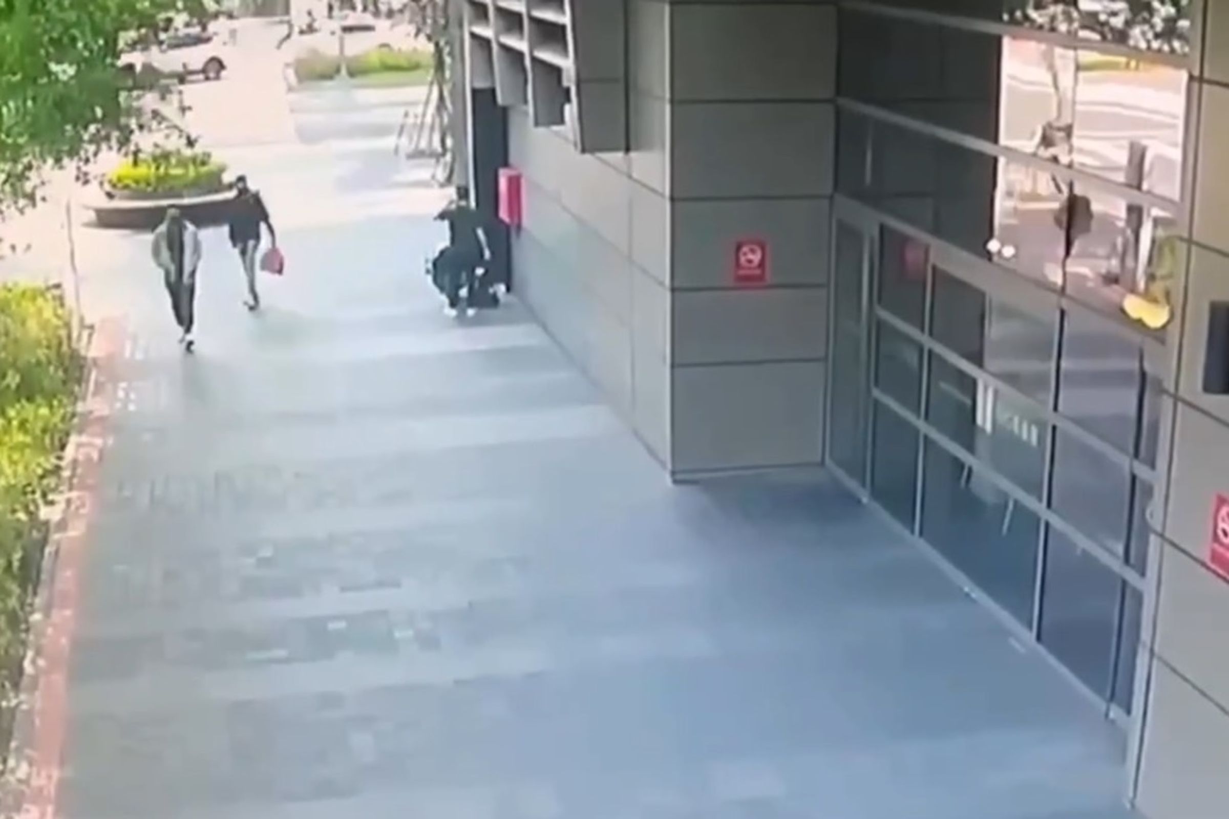 趙姓及許姓男子躲在柱子後,確認交易正在進行,隨即持刀上前搶錢。(翻攝畫面)