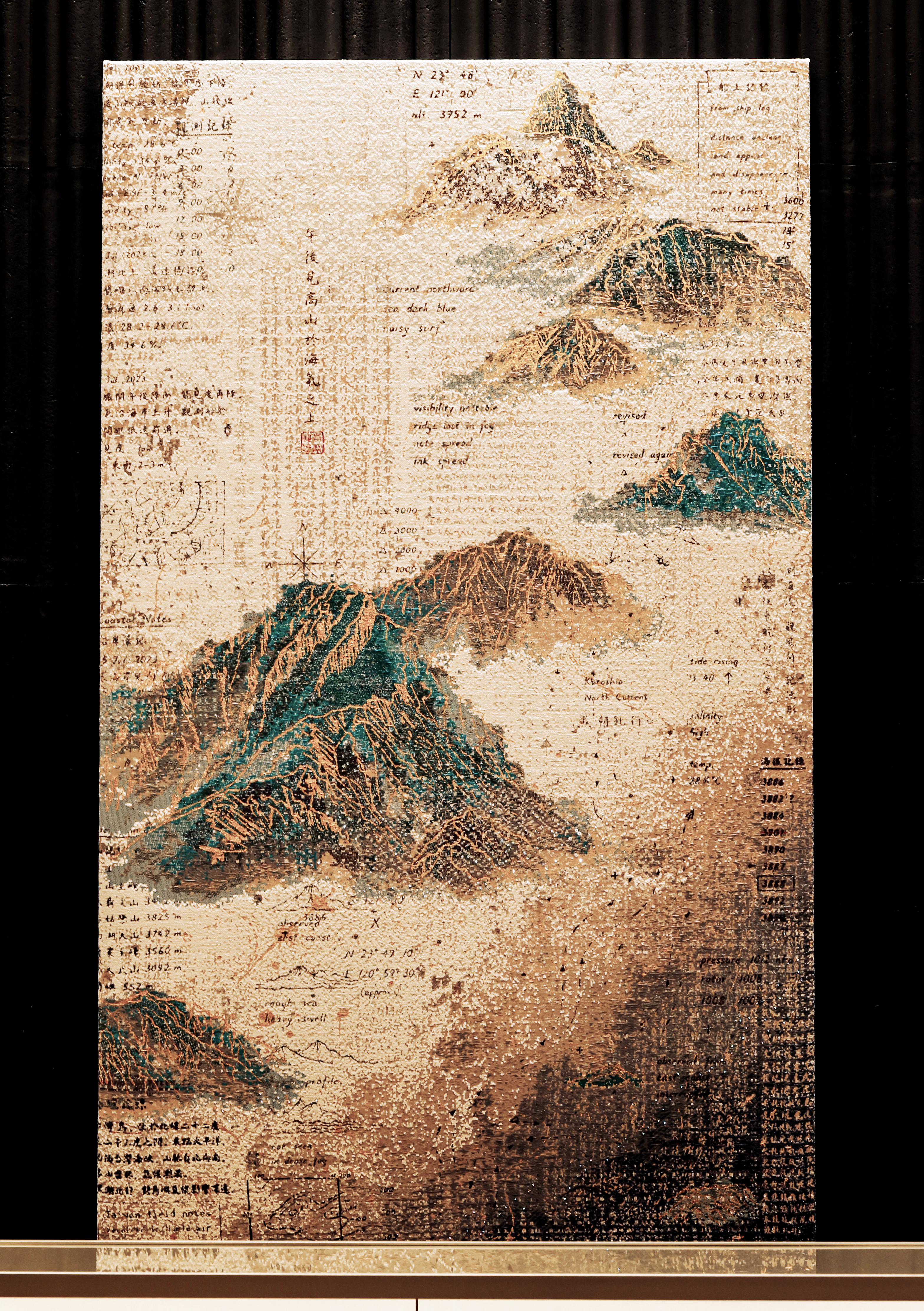 織品藝術家李偵綾創作的兩幅《島嶼地誌》作品,結合鋼筆書寫、金線編織與紙張肌理,以台灣「五嶽三尖一奇」及島嶼地貌為創作靈感,描繪山岳、黑潮、霧氣與濕潤氣候等自然意象。
