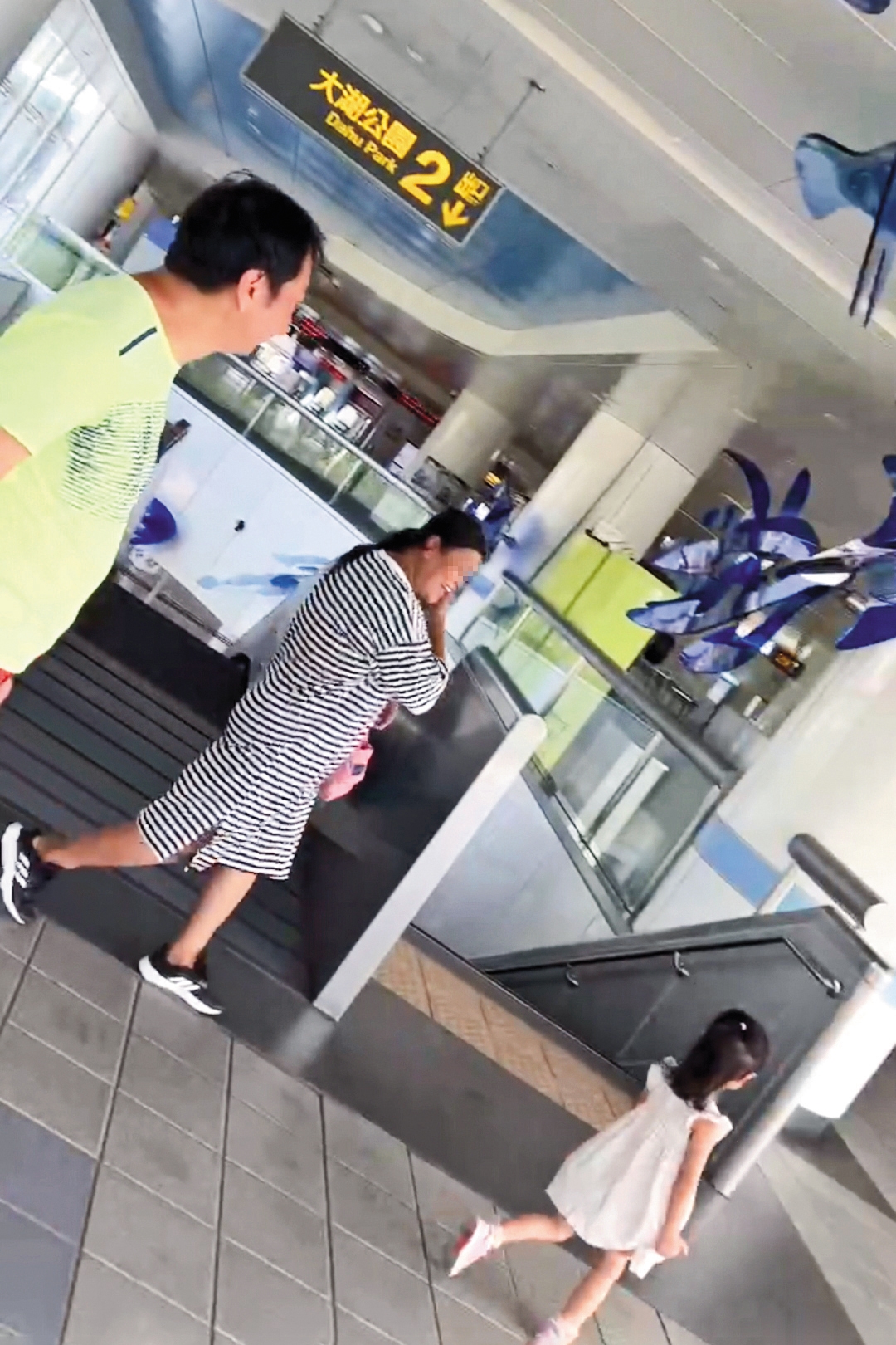 九孔（左）帶著兩歲女（右）到大湖公園玩耍結束後，與移工（中）一起進入捷運站。（讀者提供）